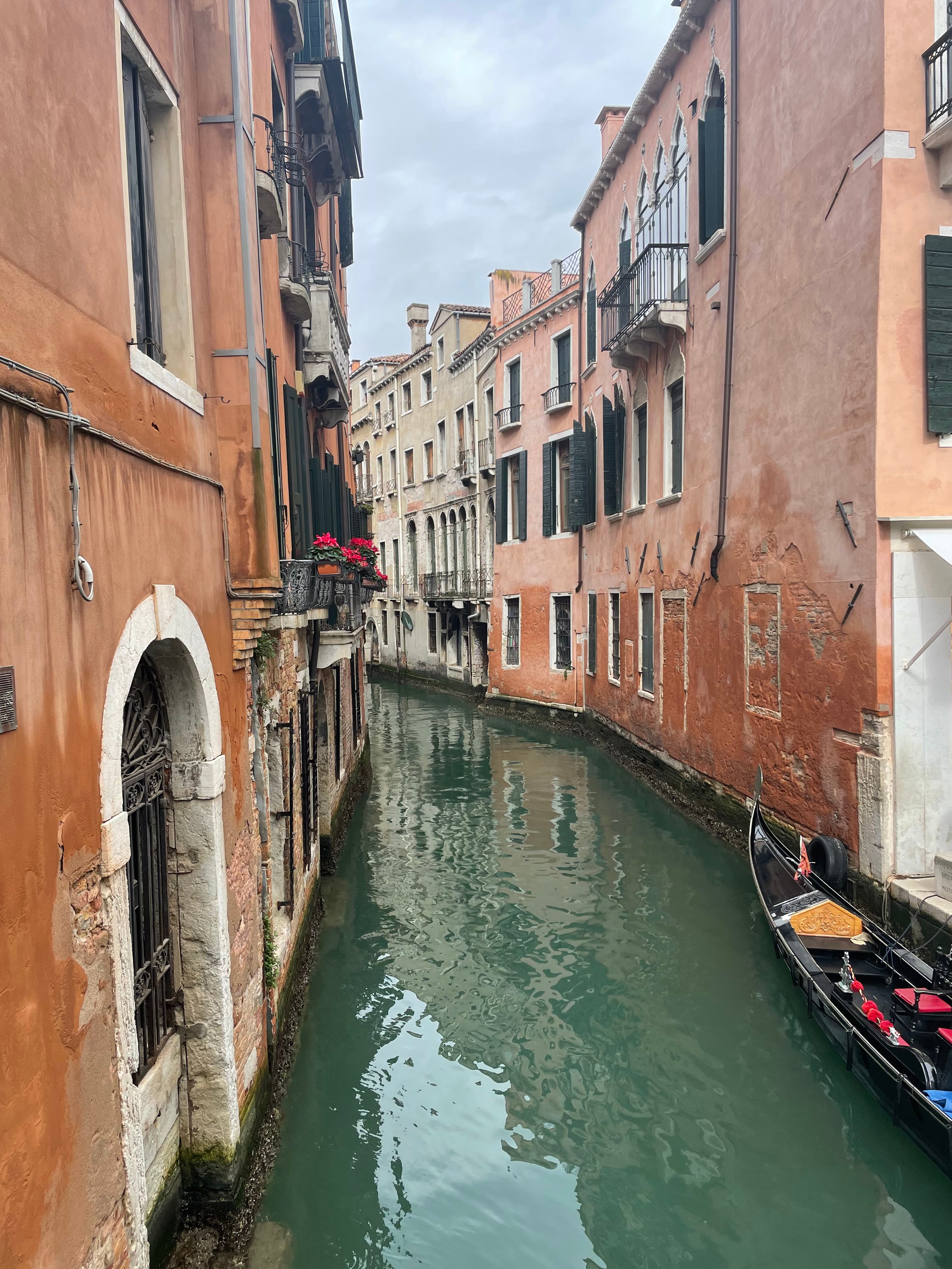 Pretty view of a narrow canal in between old buildings on a cloudy day in Venice, Italy