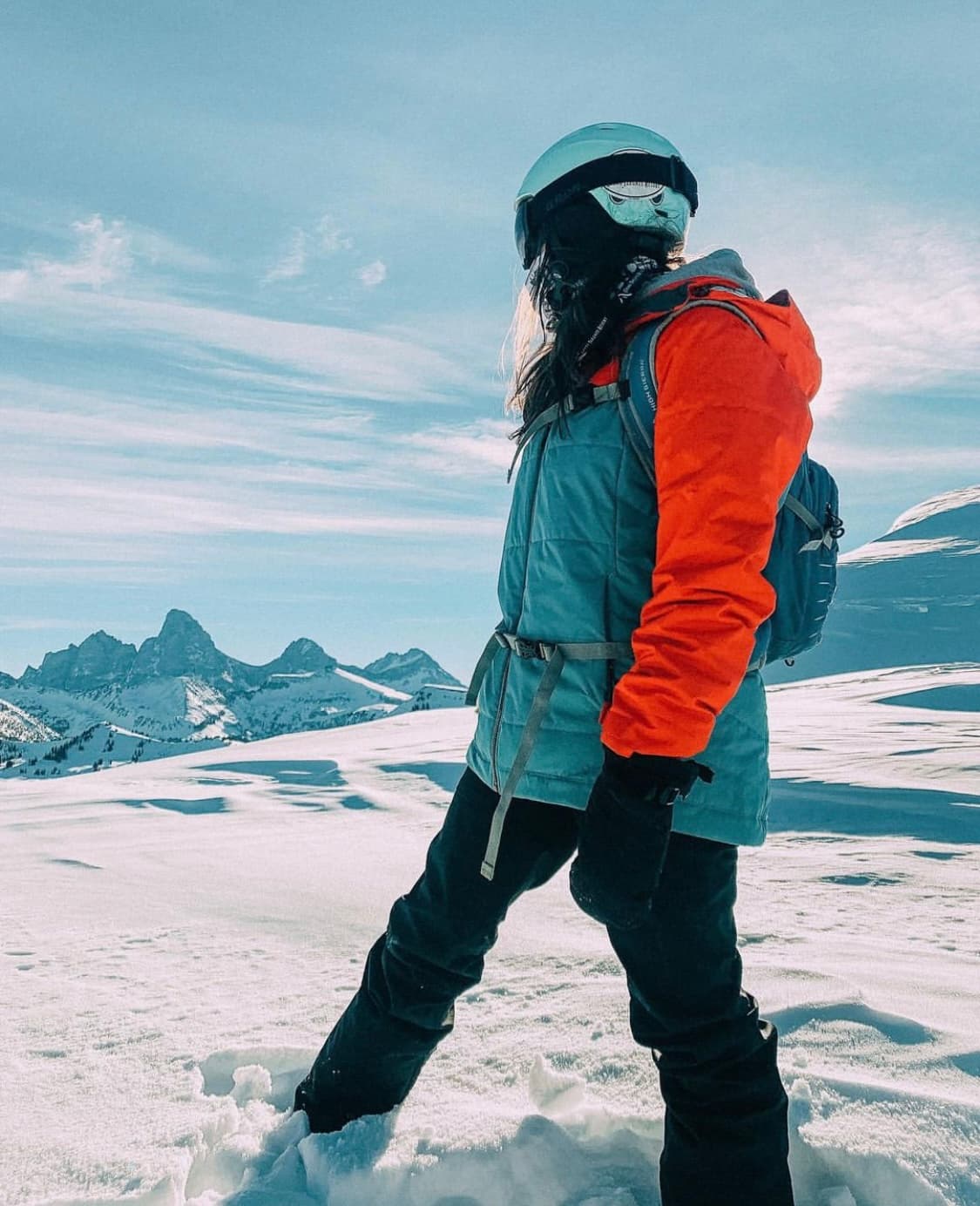 Advisor in a snow jacket and ski helmet standing on a snowy ridge.