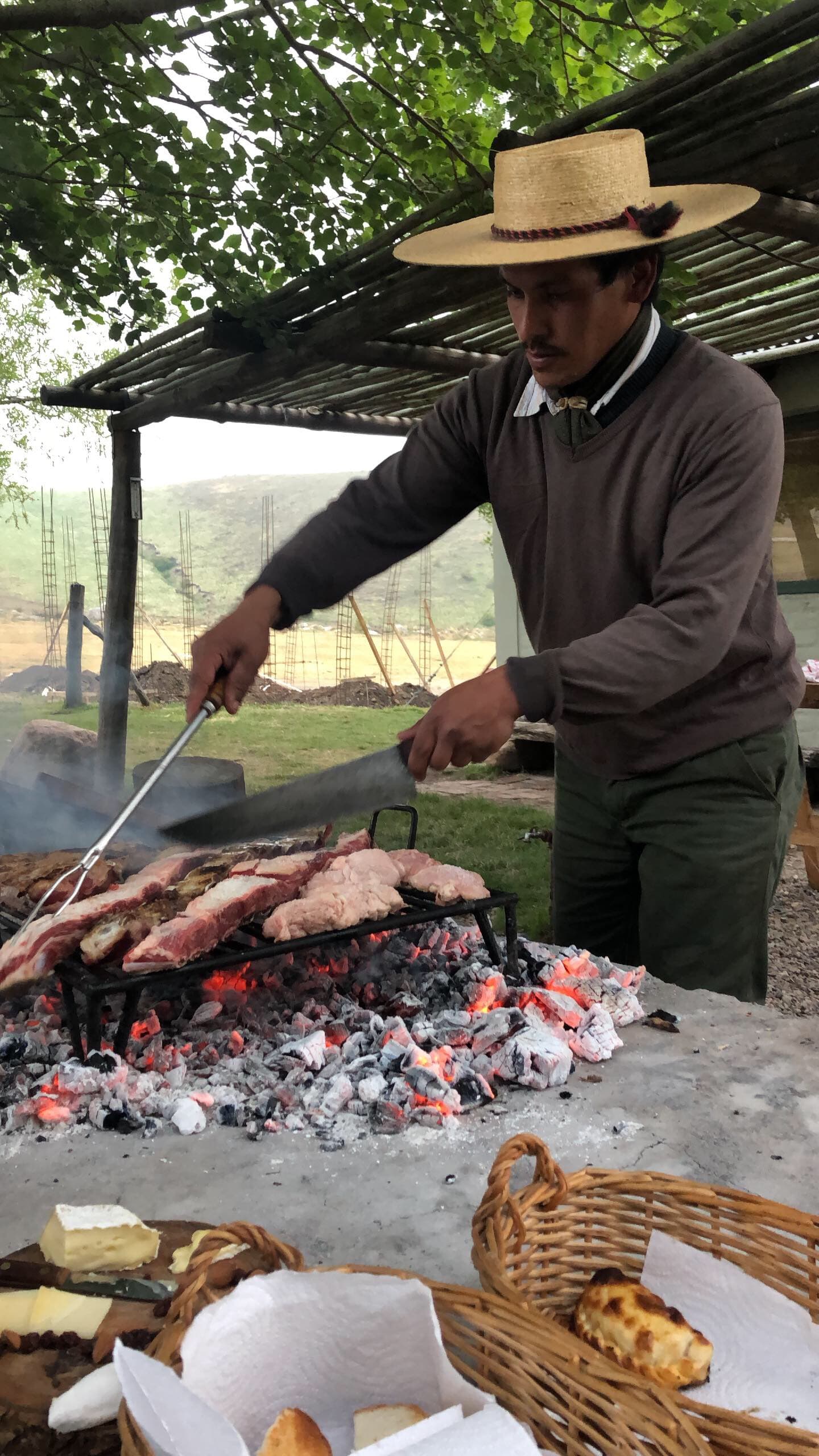 Chef prapering grilled food over charcoal under trees on a sunny day