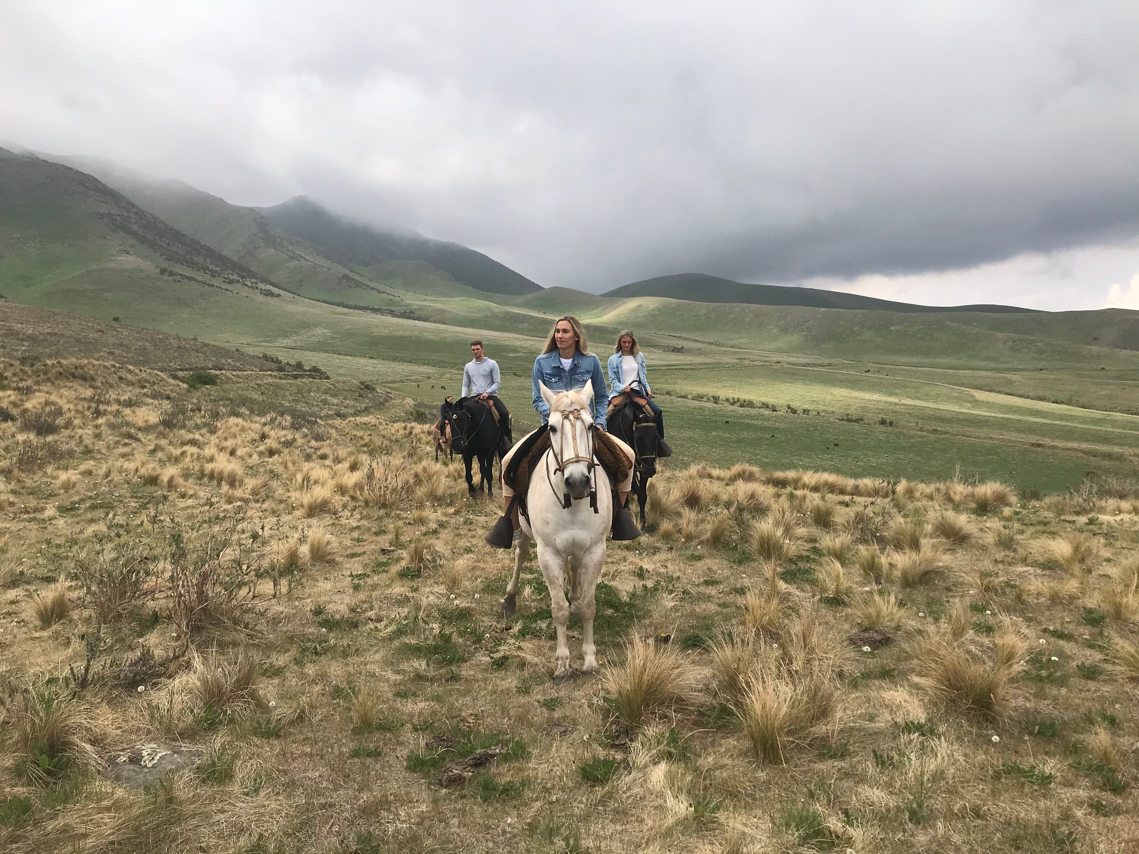 Advisor on a horse with two others on a slope on a cloudy day