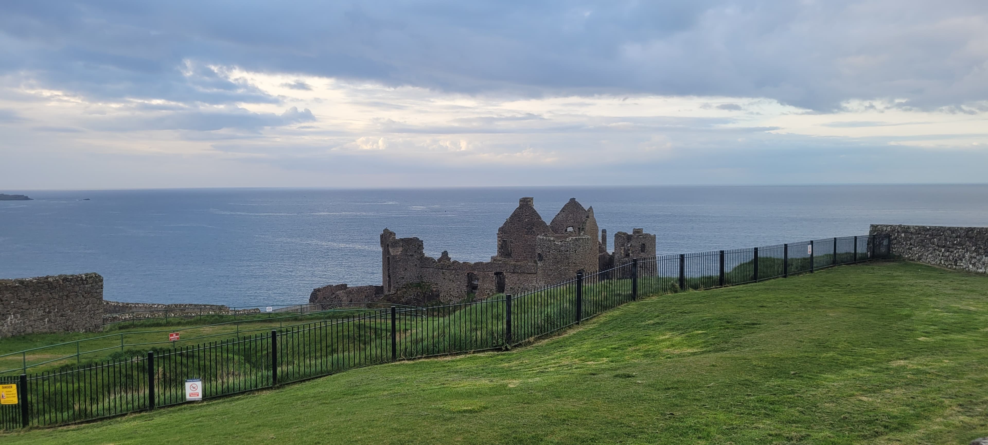 Coastal view of historical ruins overlooking the sea on a cloudy day.