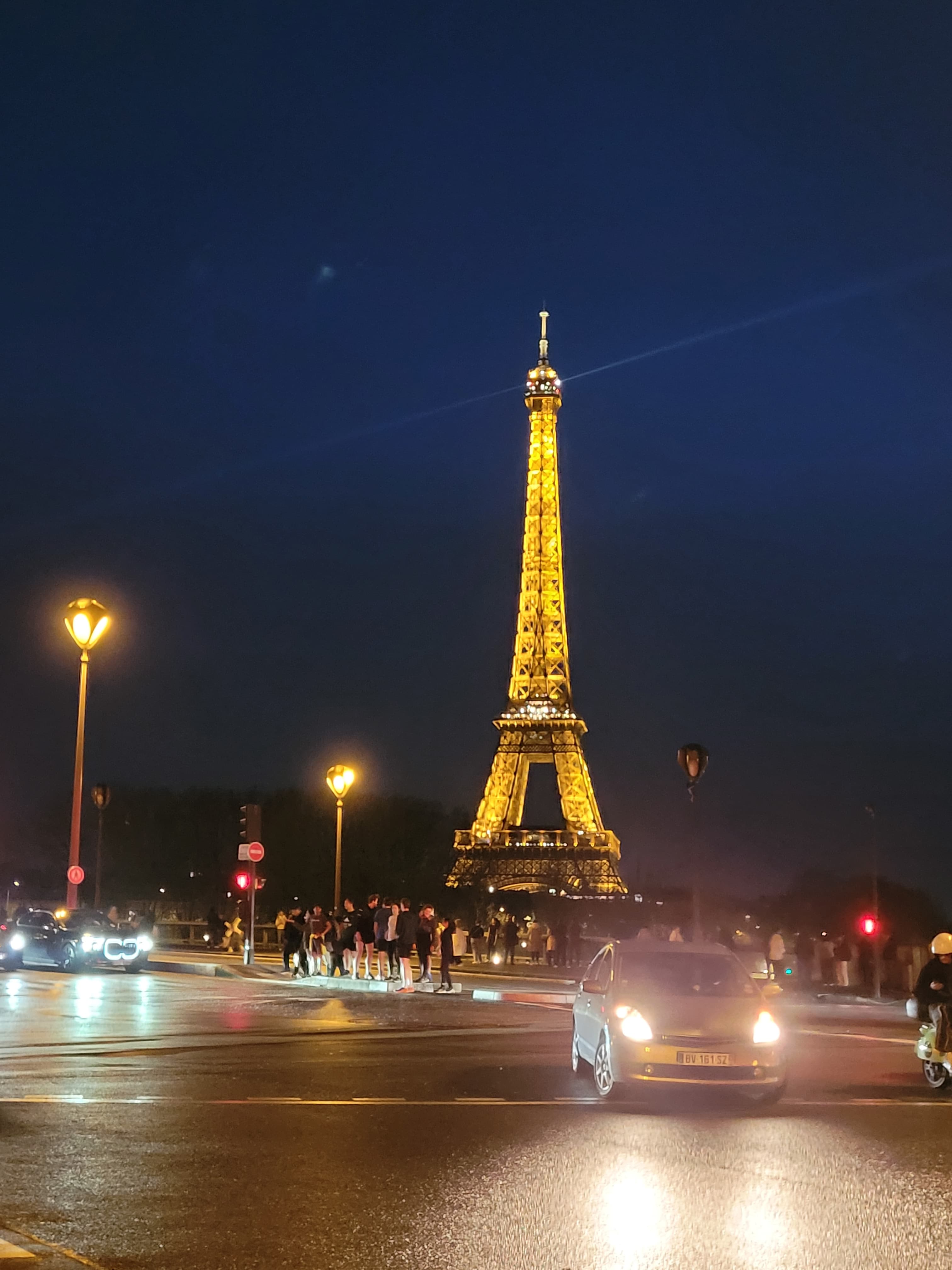 A street view of the Eiffel Tower lit up at night.