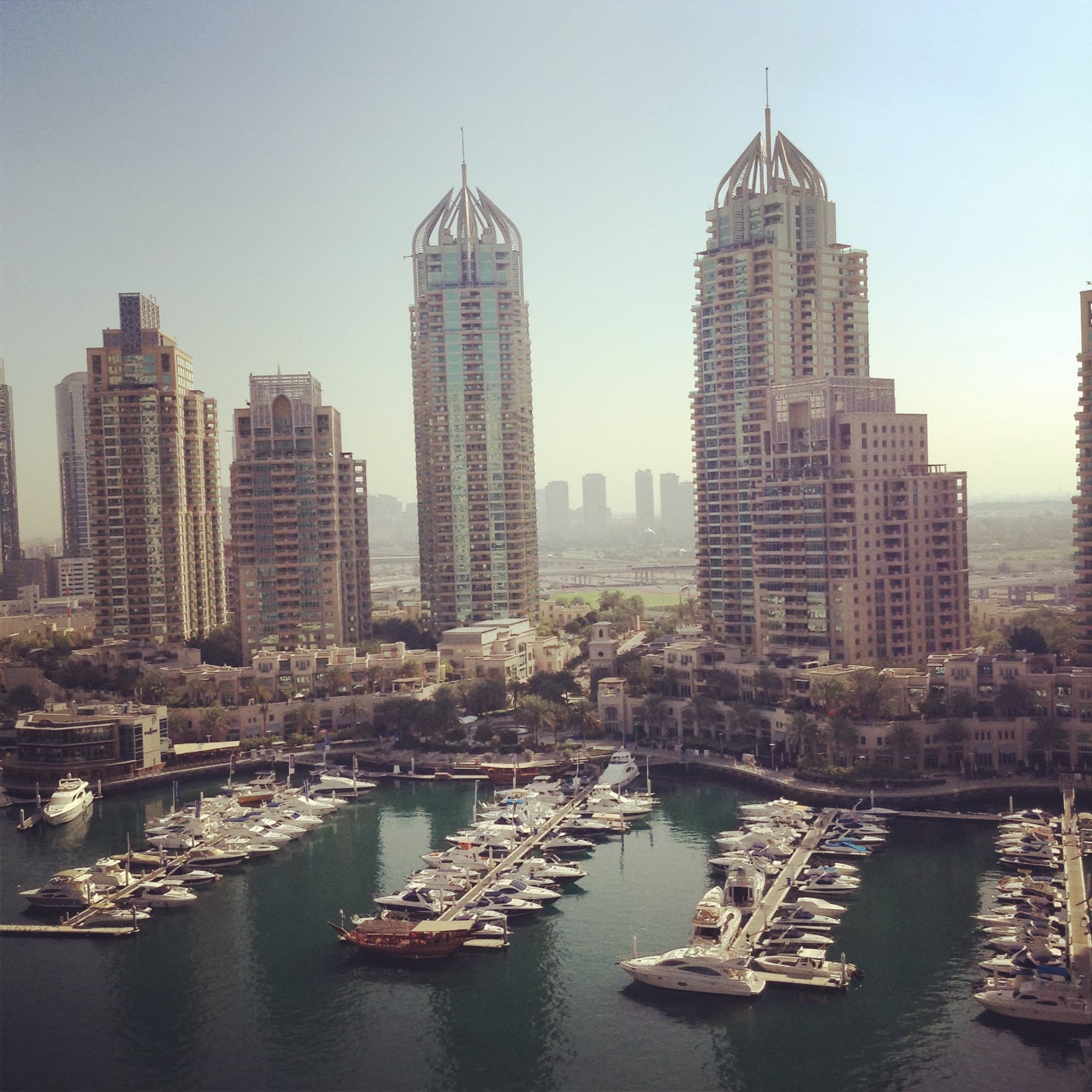 An aerial view of a city with sky scrapers and a body of water with boats docked during the day.