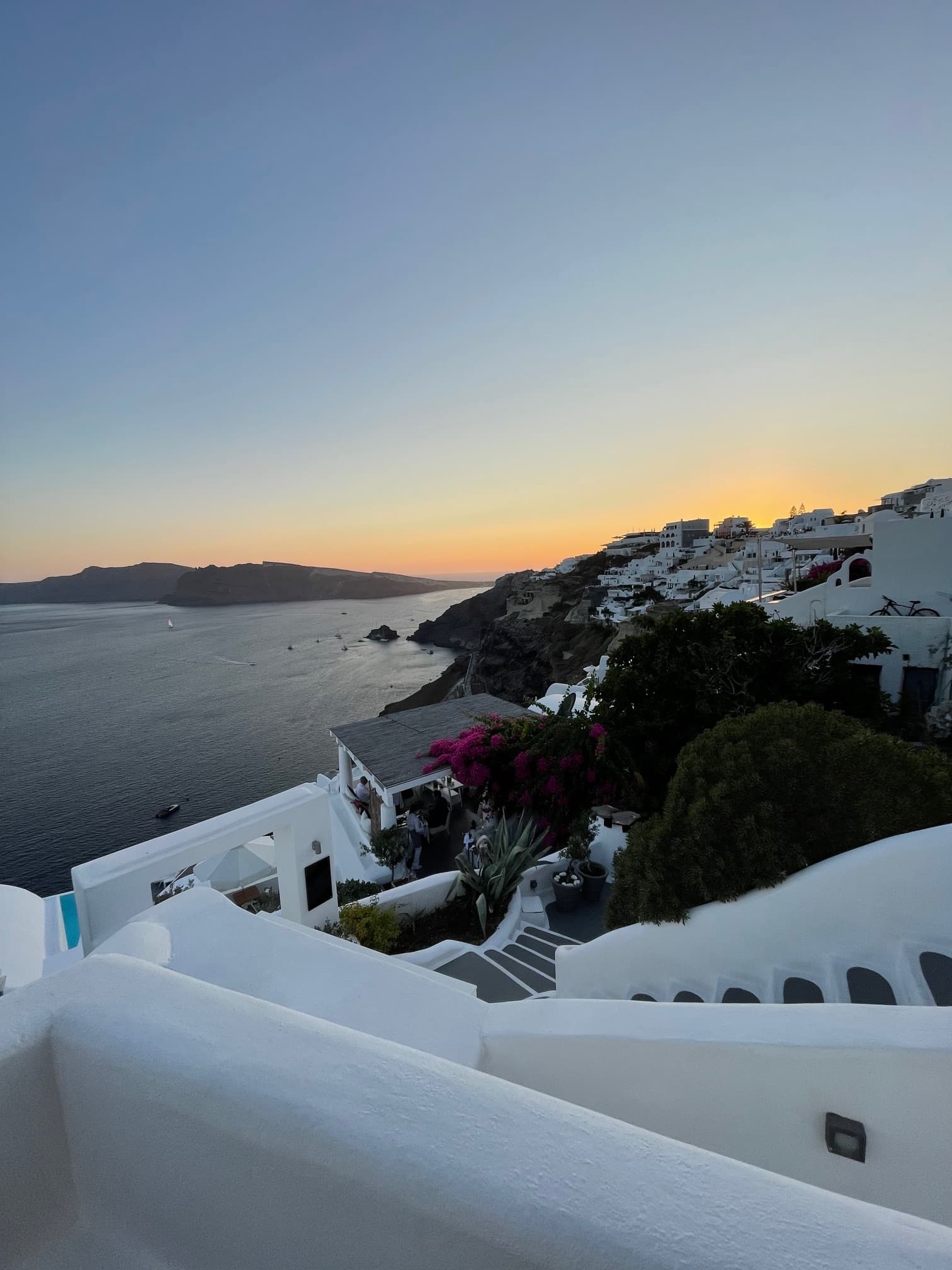 A view of white buildings over the ocean at sunset.