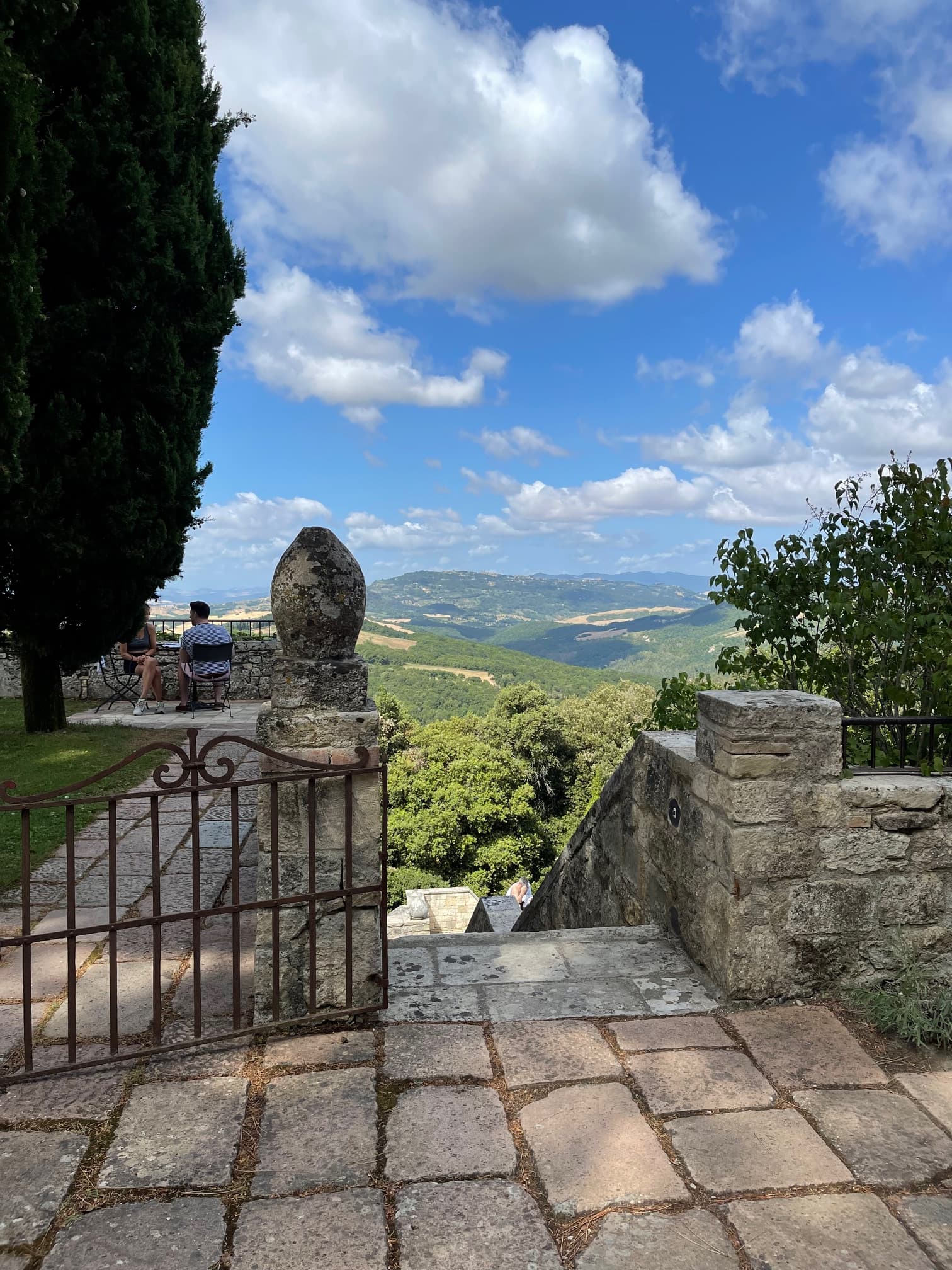 A view from a stone staircase overlooking a lush green hillside.