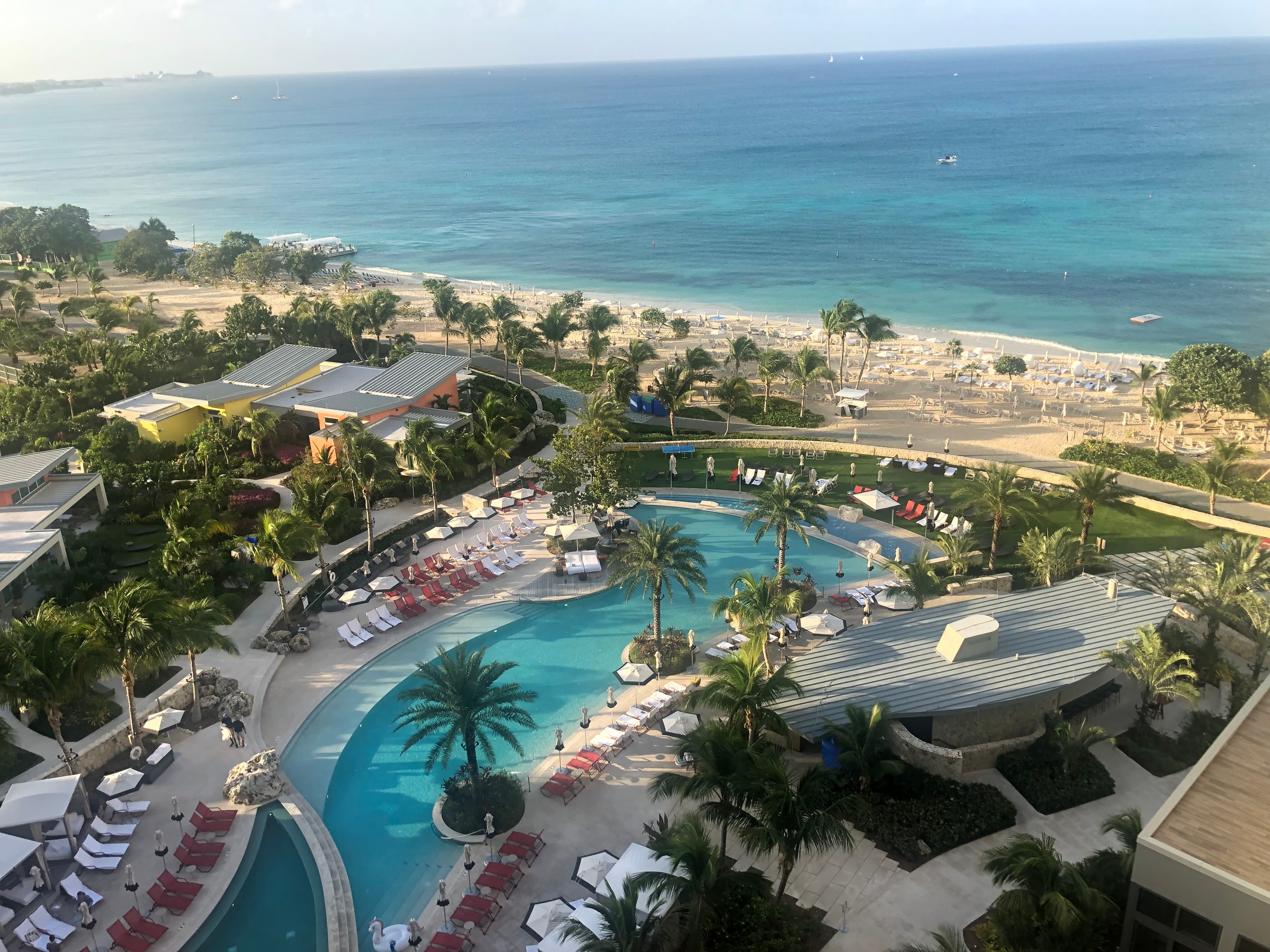 An aerial view of a hotel resort pool overlooking the beach and ocean.