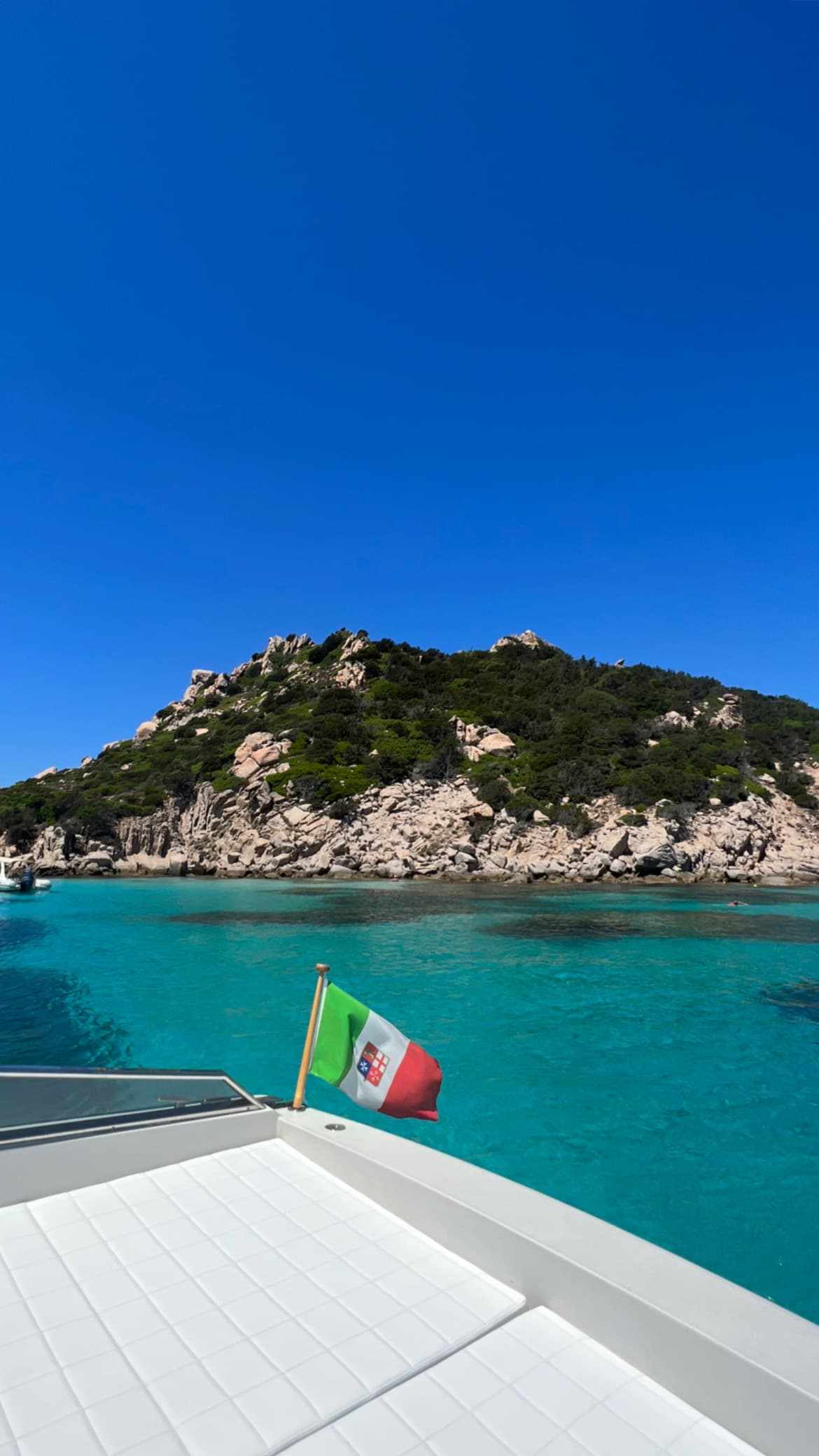 View of clear, blue waters off a boat's edge on a sunny day.