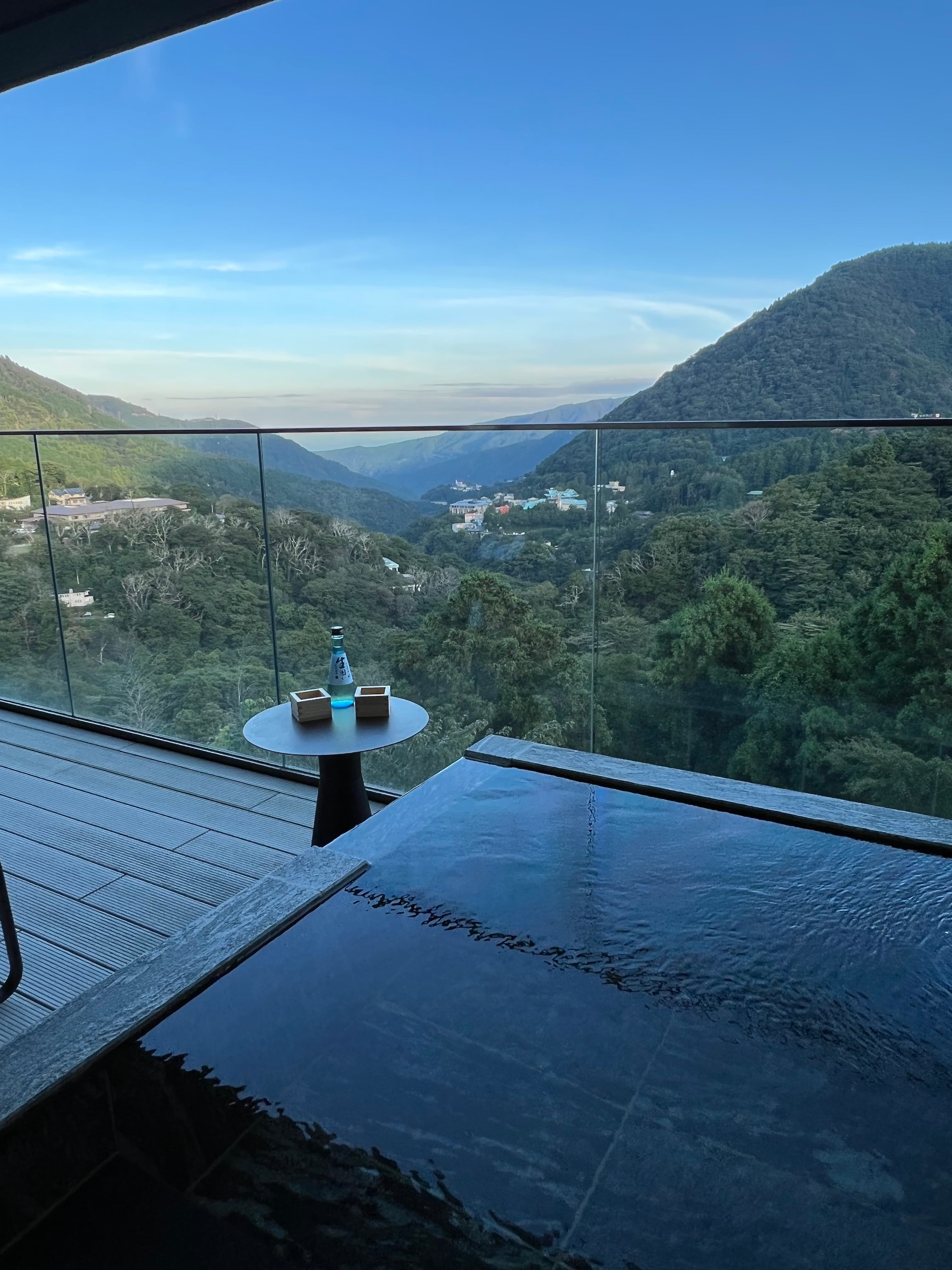 A mountain scene unfurls below a deck view on a sunny day.