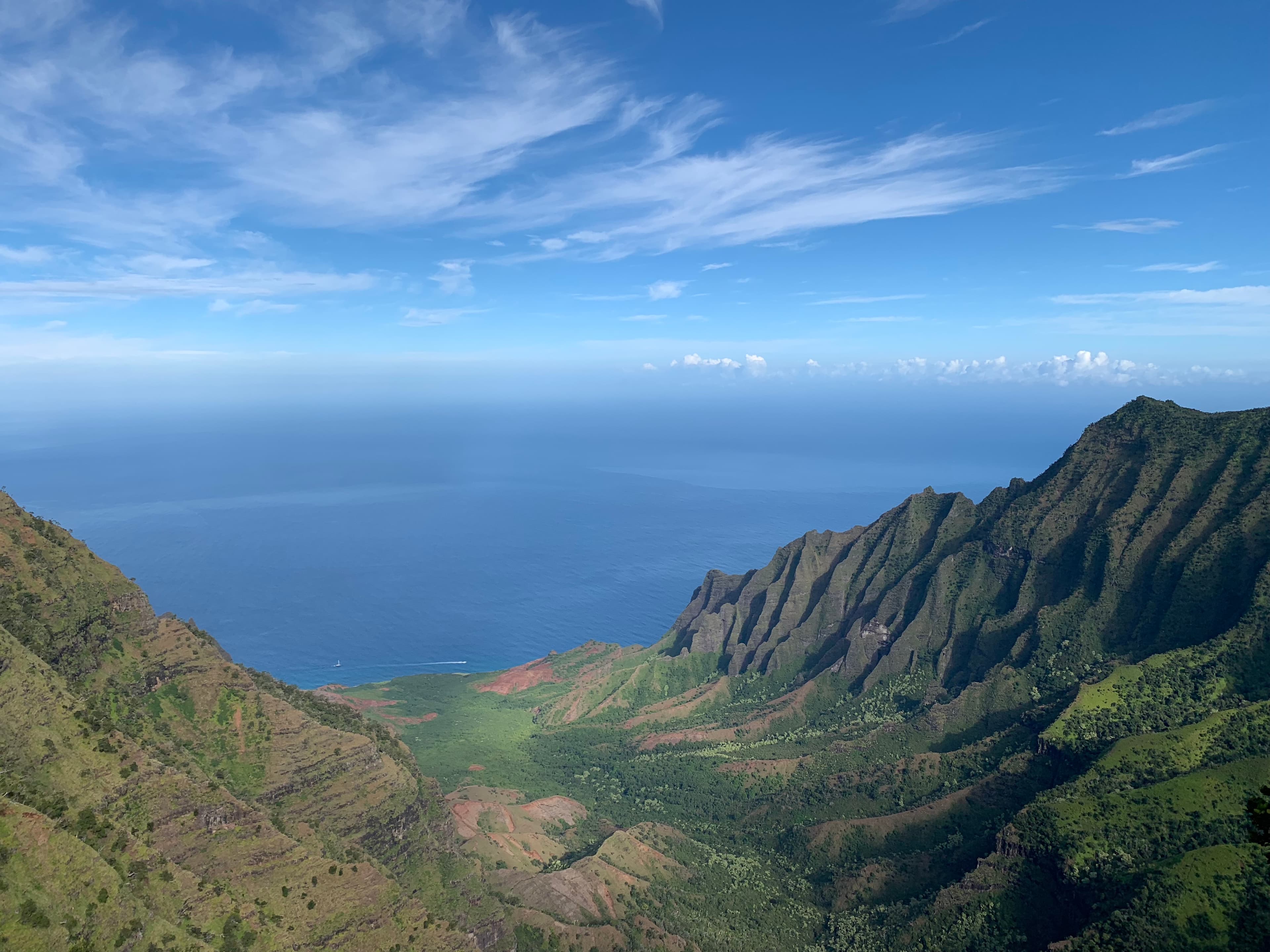 A view of clear blue waters from an island hilltop on a sunny day.