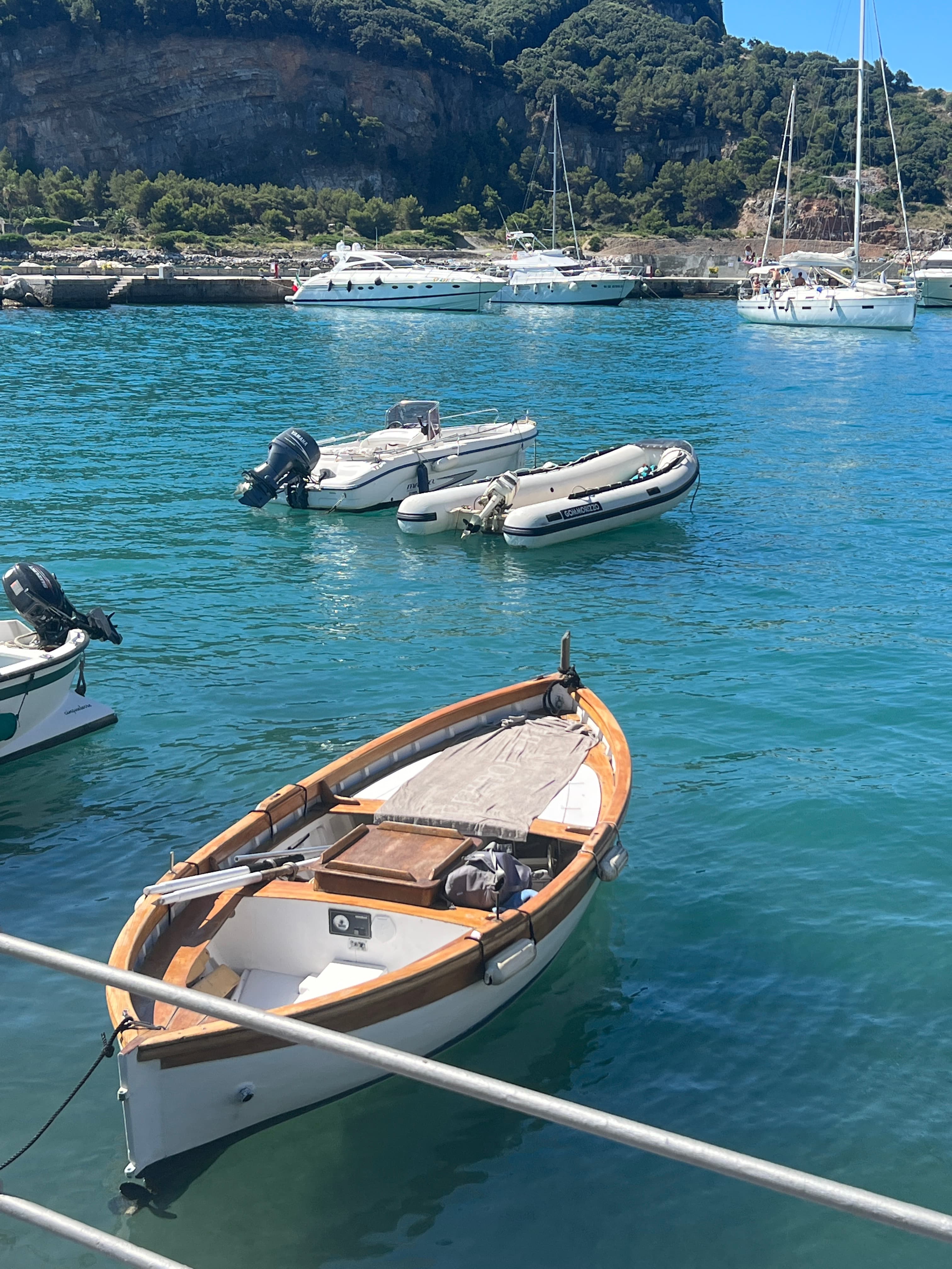 Pretty view of small boats docked on a blue sea with green hills in the distance on a sunny day