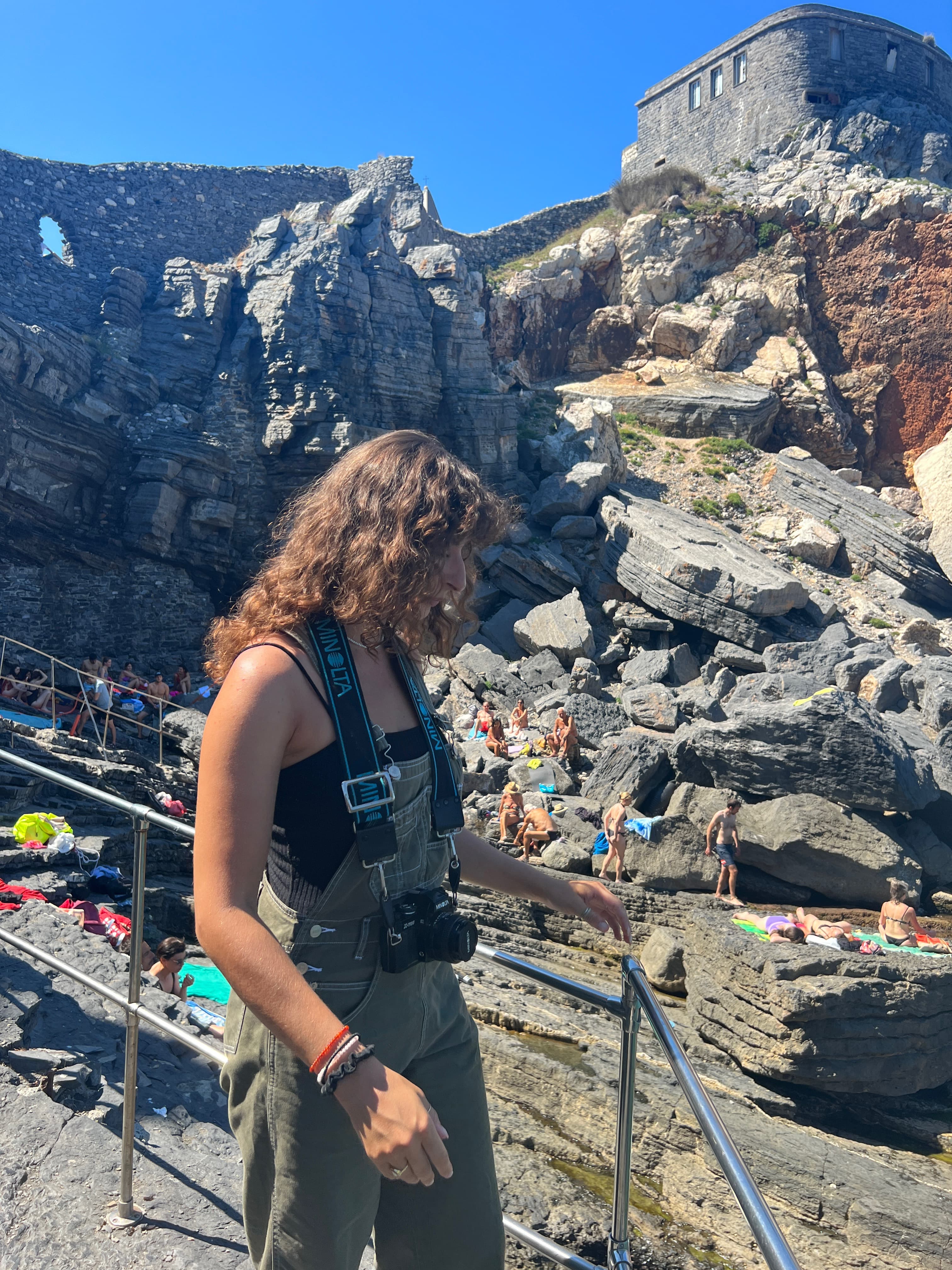 Jordan with a camera around her neck on a sunny day in a rocky landscape