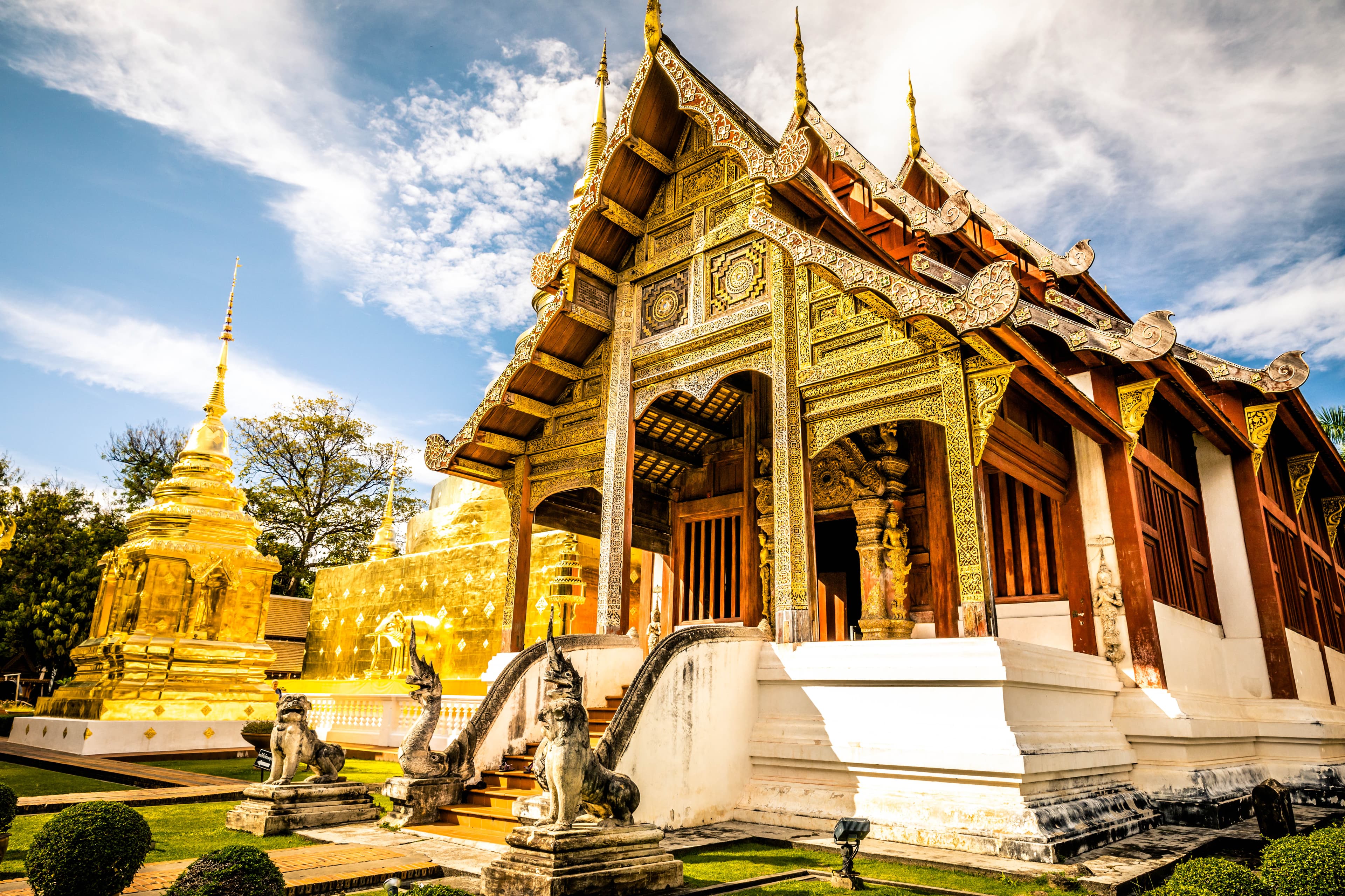 View of a beautiful, ornate golden temple with statues in front on a sunny day