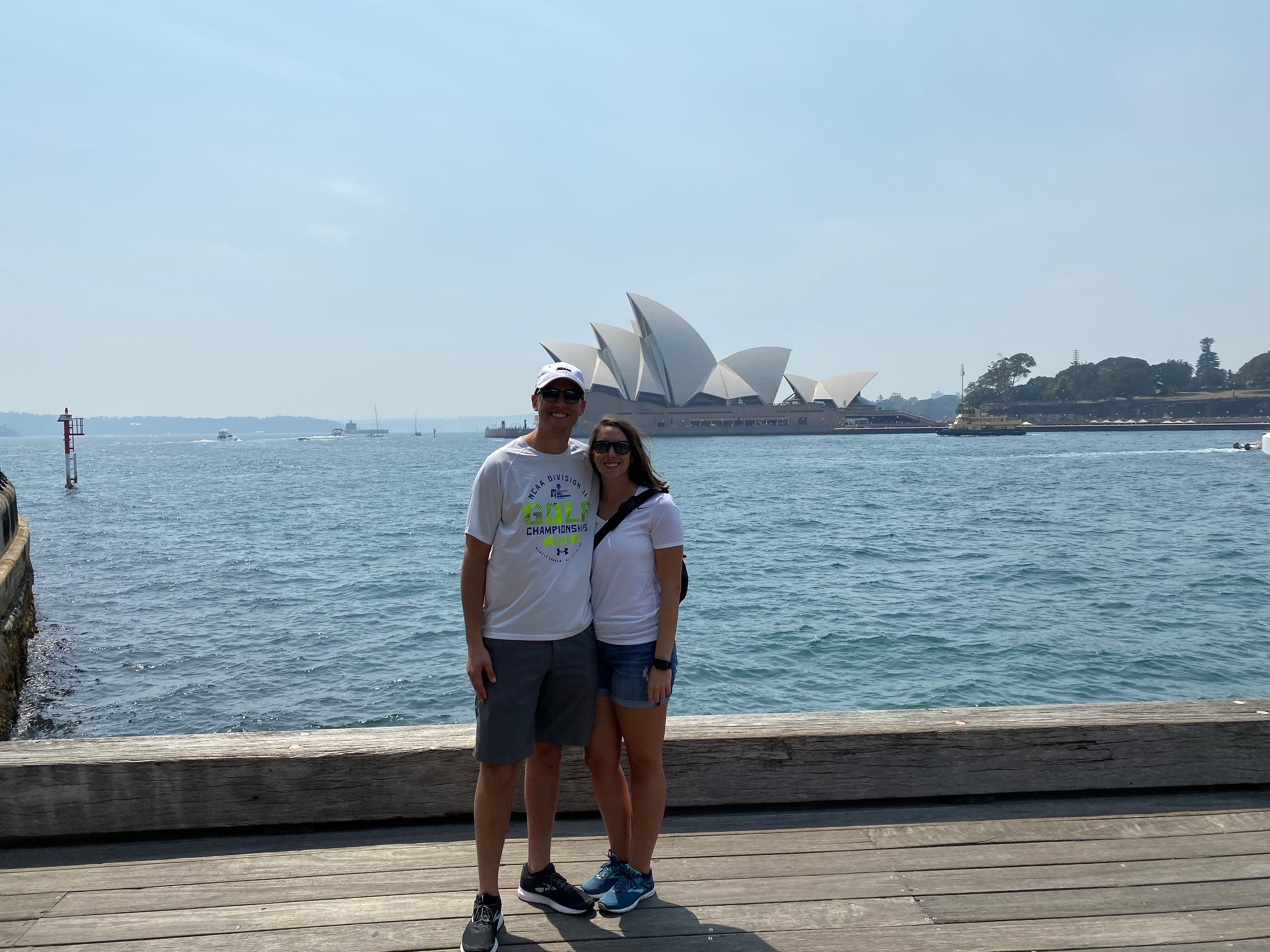 Couple poses in front of water and the Sydney Opera House.