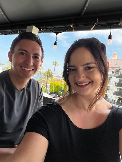Jadyn and a man pose for a selfie outdoors with a landscape with palm trees visible behind them