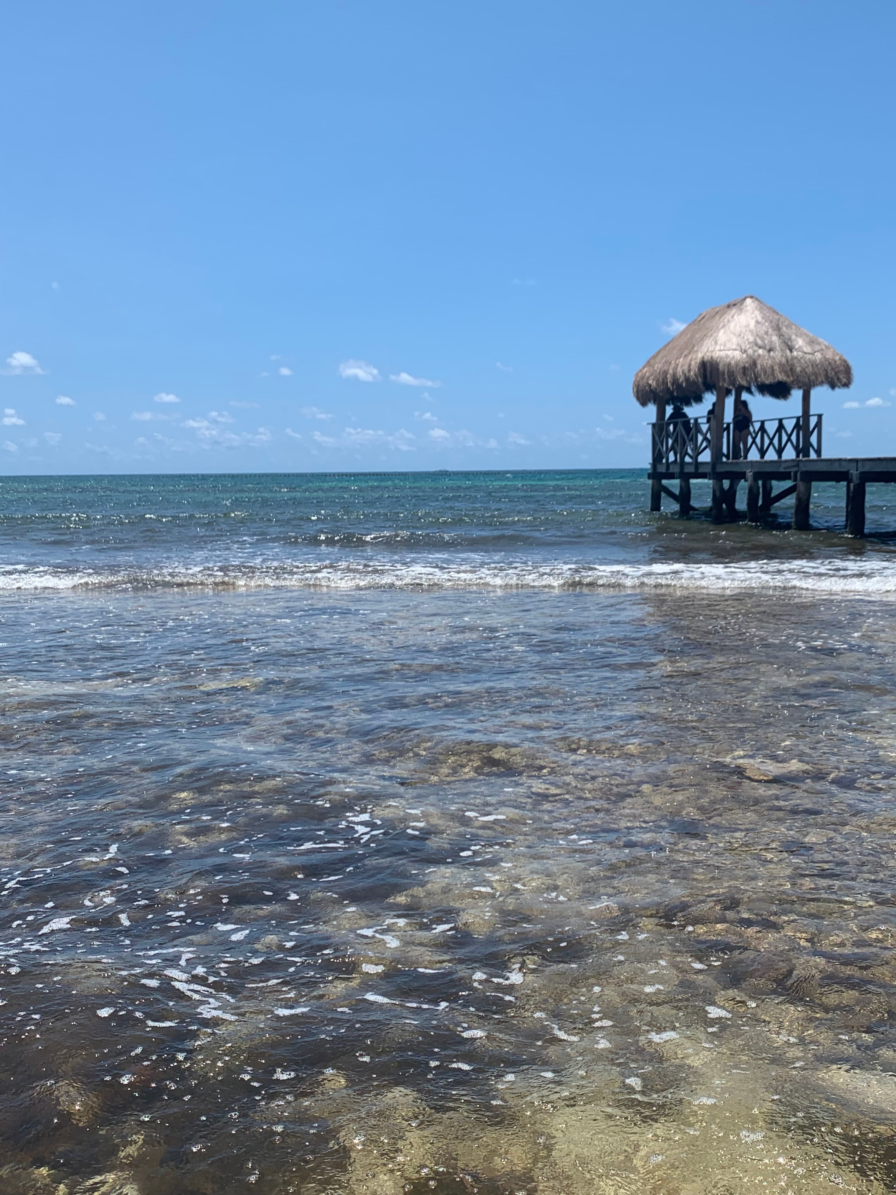 Shallow ocean front in Cancun with a pier.