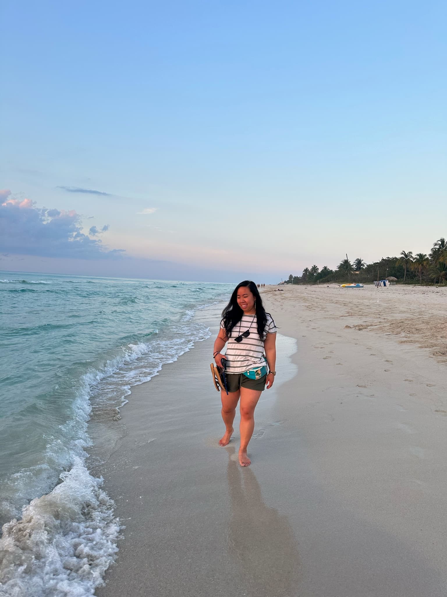 Chelsey standing near the ocean on a beautiful sandy beach at sunset