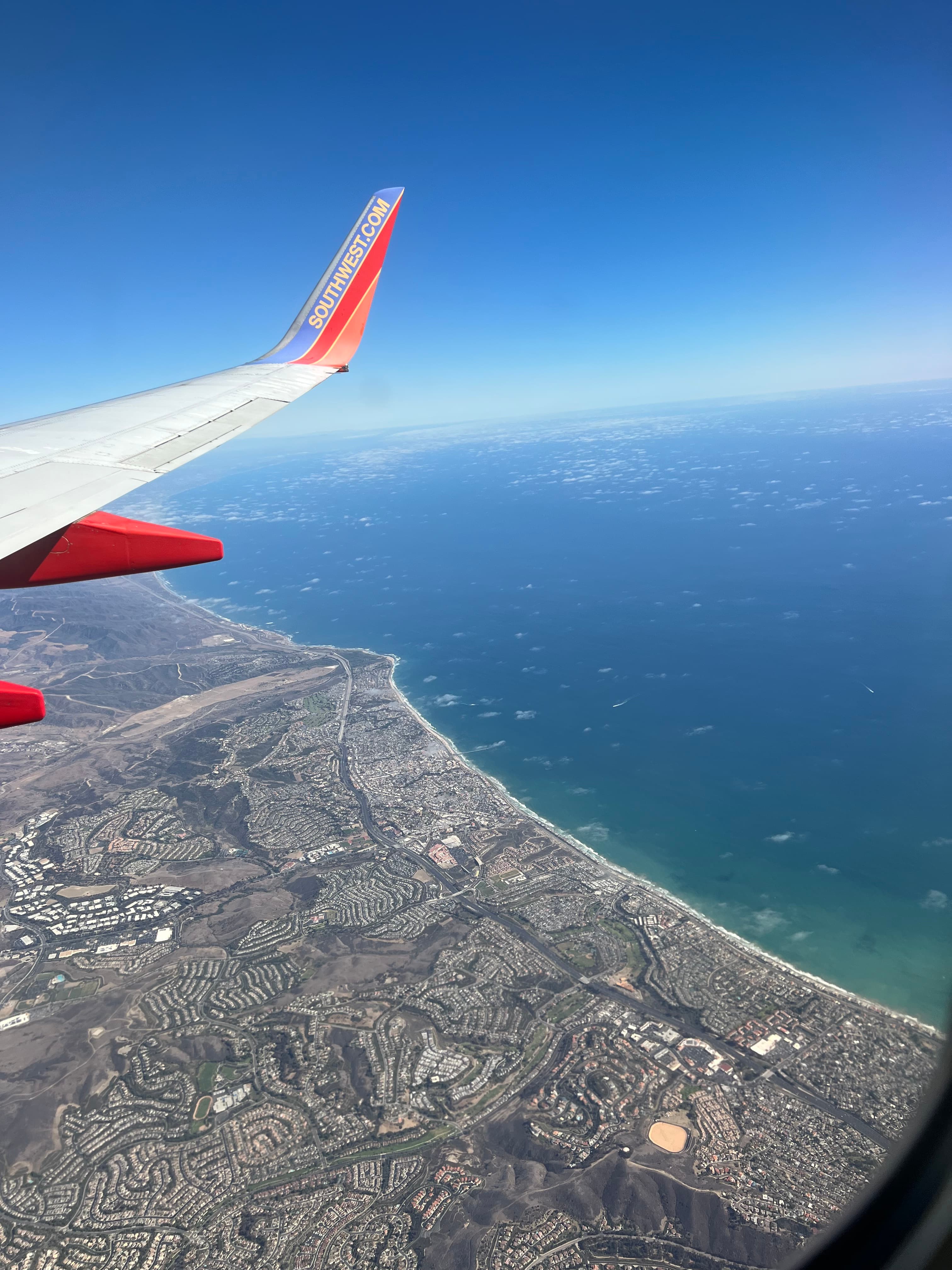 View of the coastline and sunny skies as seen from the window of a plane