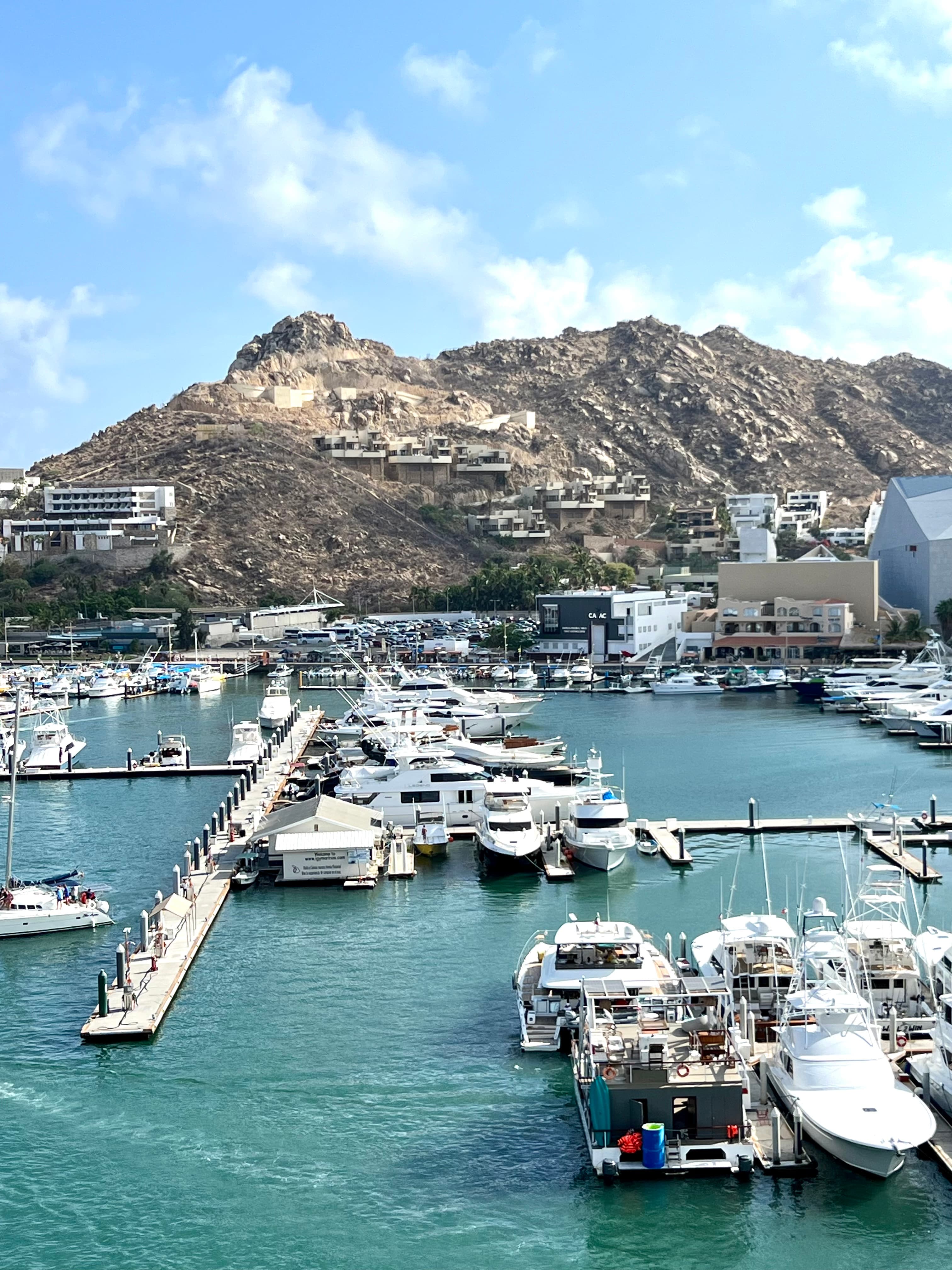 Crystal blue waters with boats floating and hilly terrain in the back.