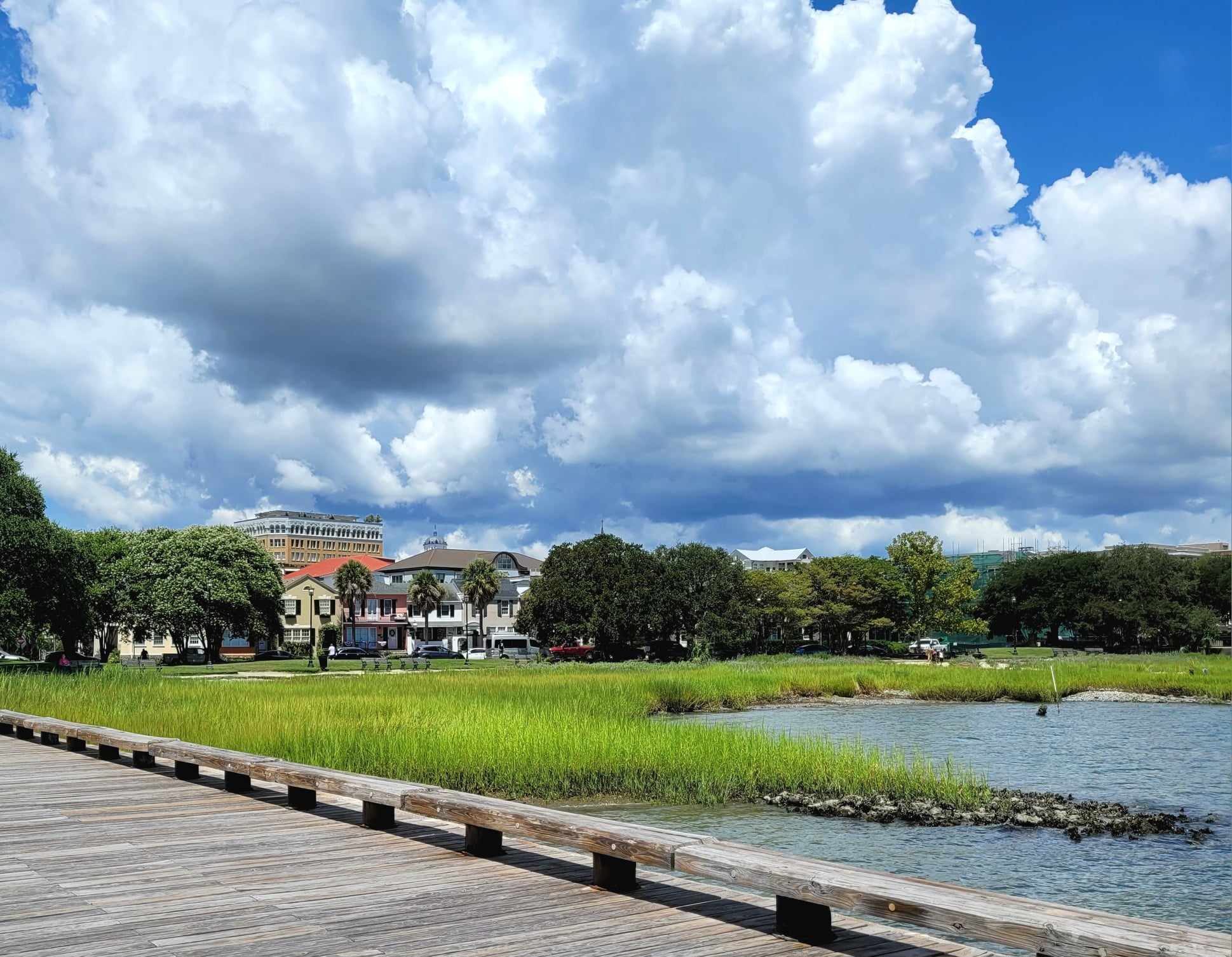 Clouds and blue sky over a boardwalk and water.
