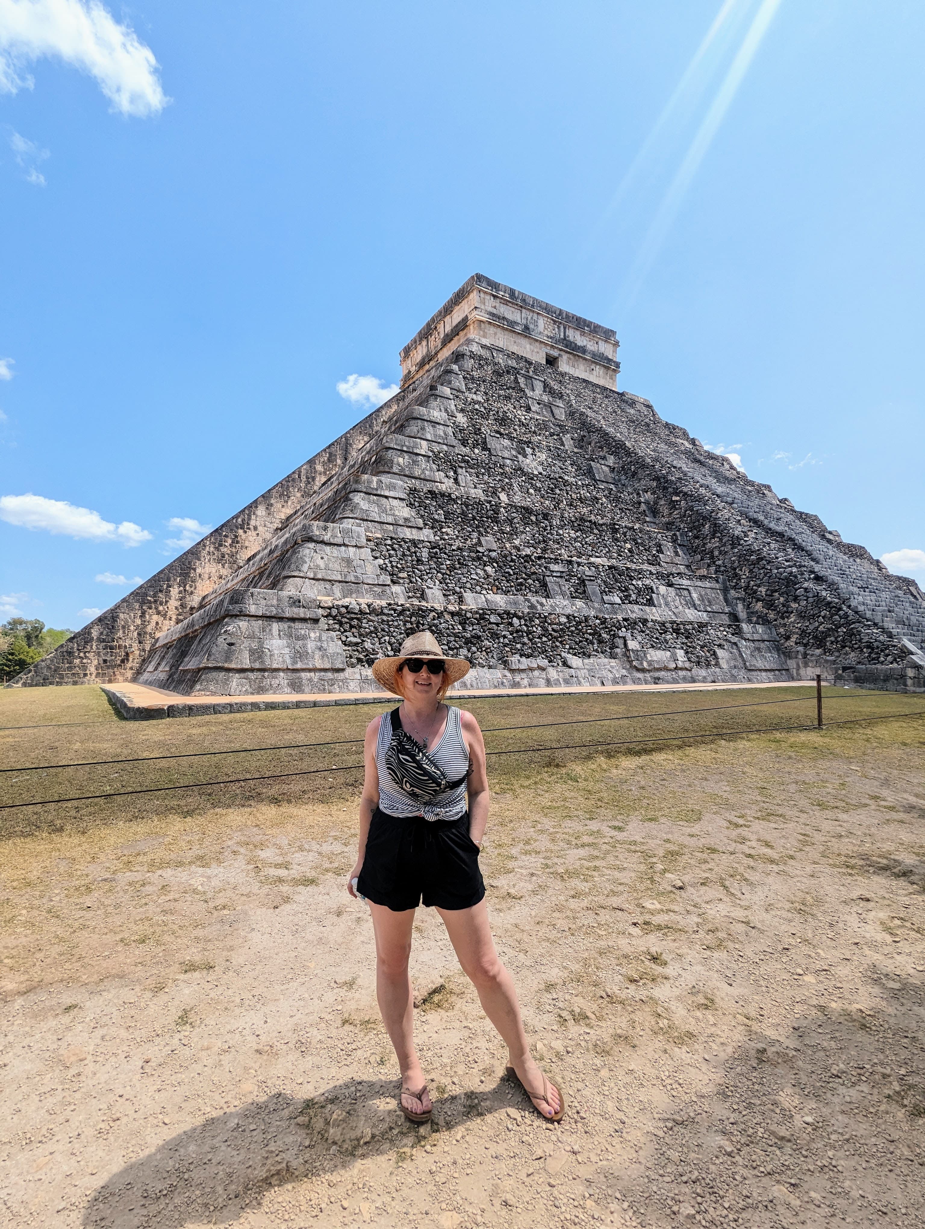 Advisor posing for an image during the day with ruins in the distance and a clear sky.