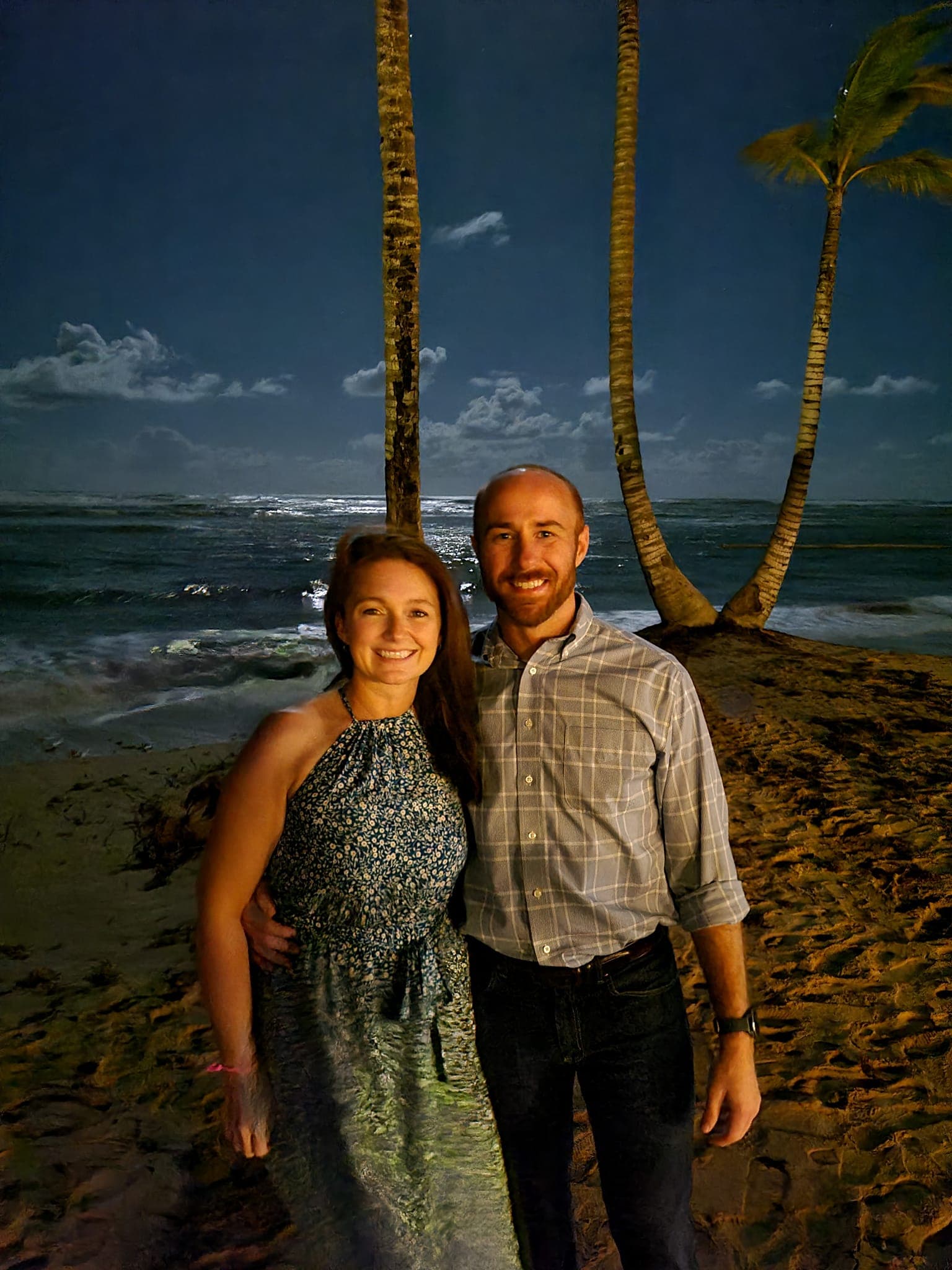 Kayla and a man with their arms around each other on the beach at night