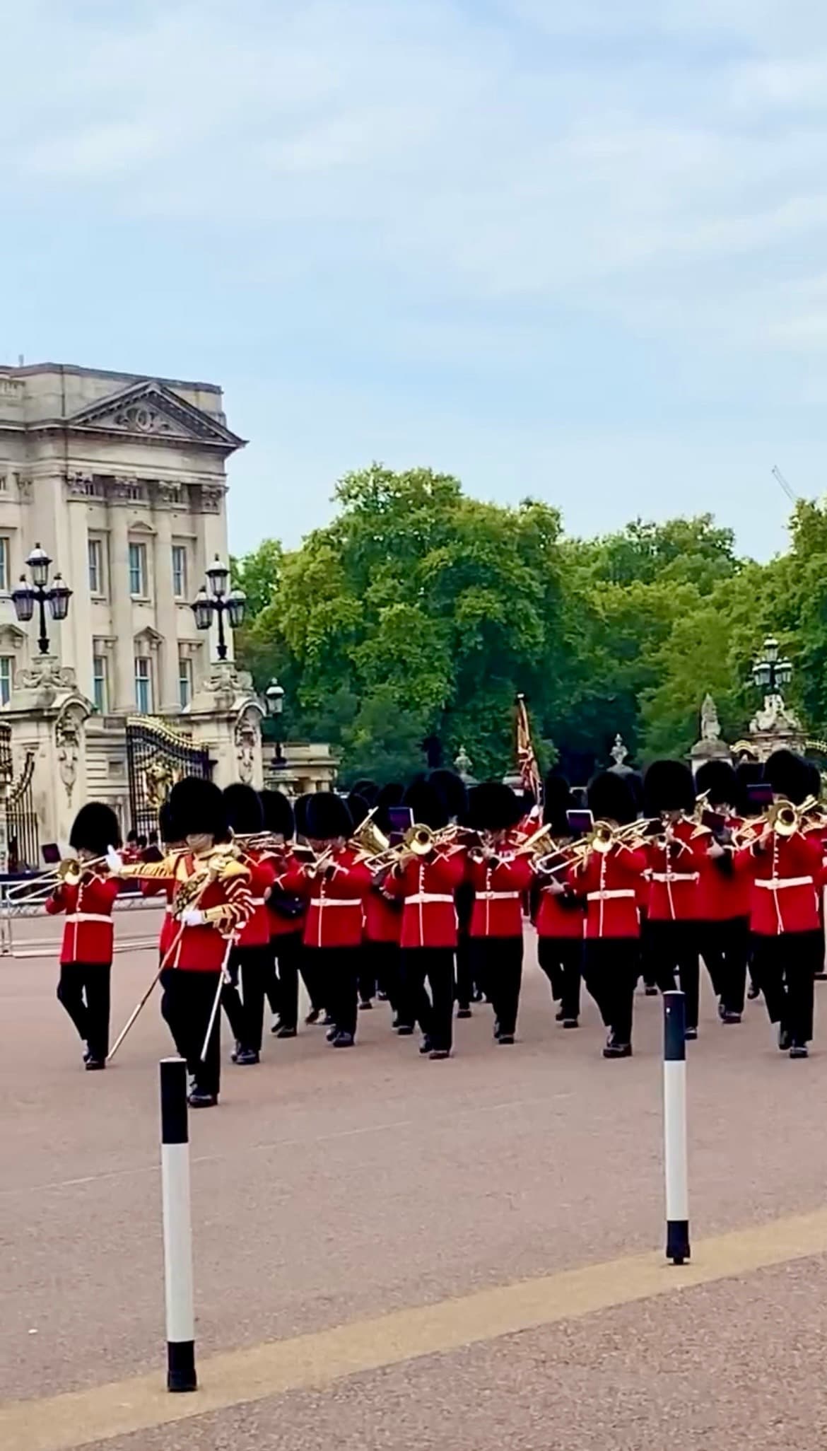 Men in red uniforms marching outdoors during the daytime.