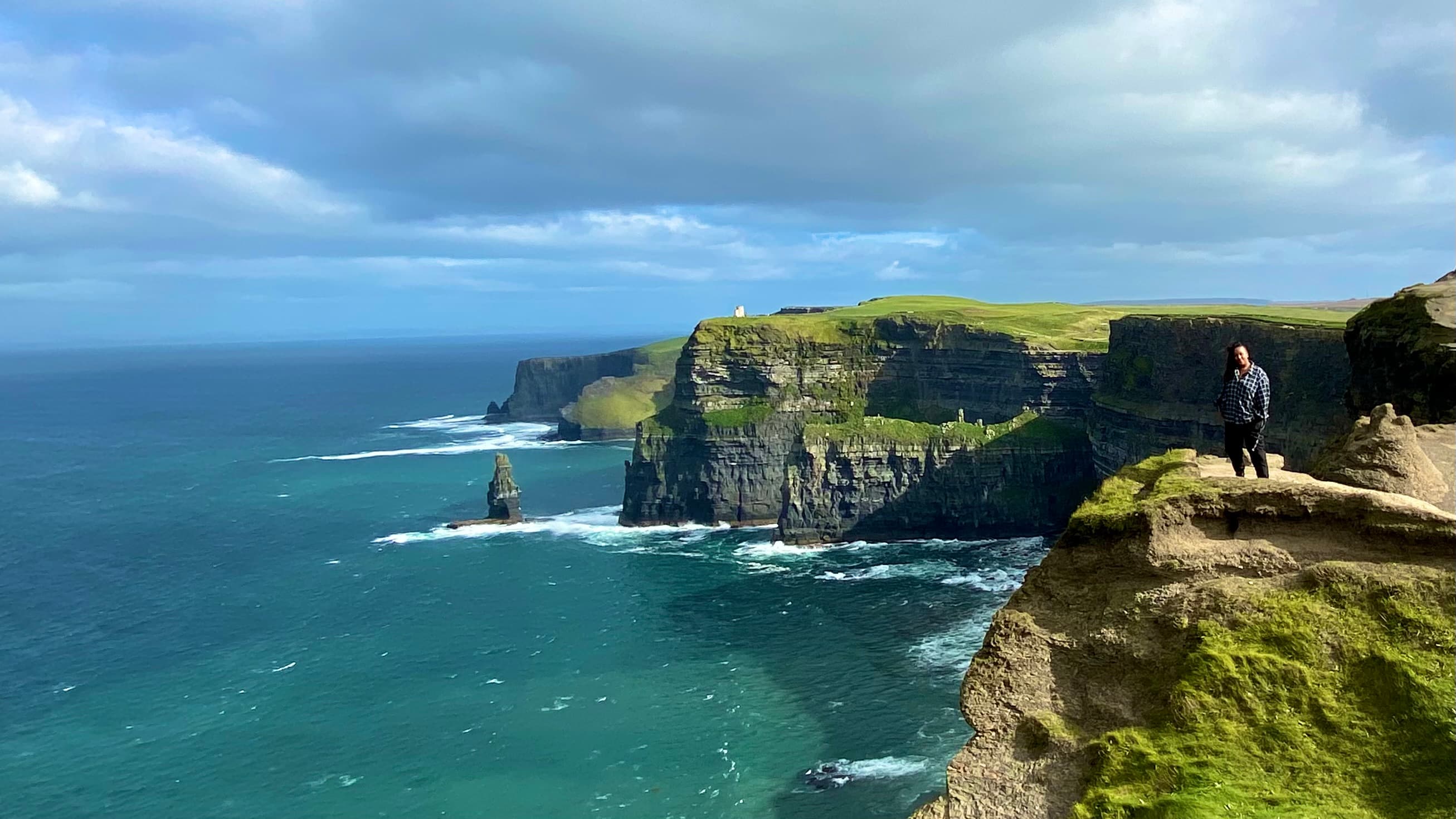Advisor posing on the edge of a cliff with the ocean surround it.