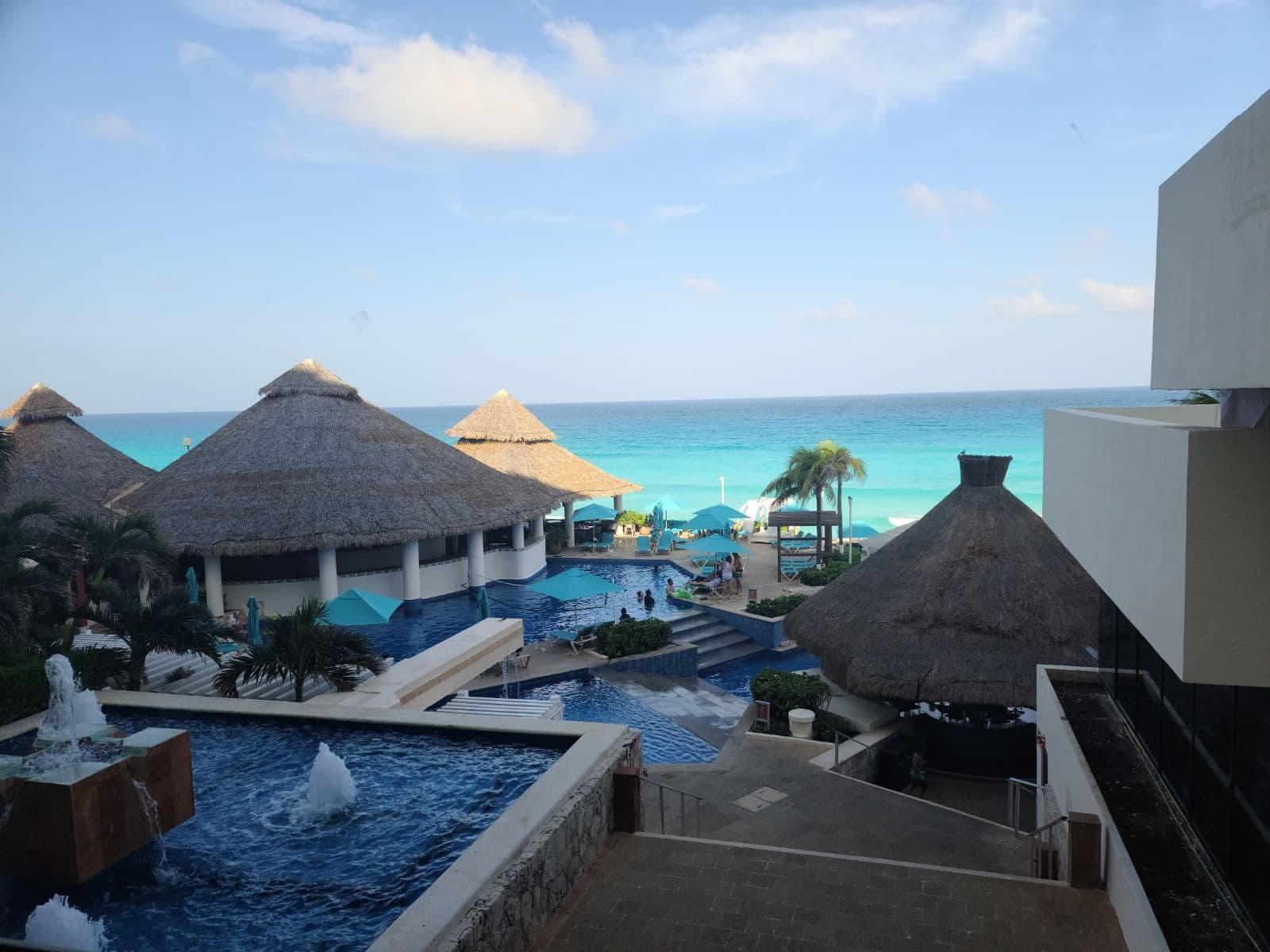 Pretty view of a resort pool and surrounding buildings overlooking a turquoise sea on a sunny day