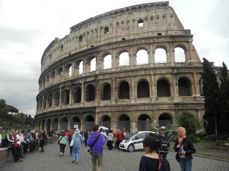 Close up view of the Colosseum in Rome with many pedestrians nearby on a cloudy day