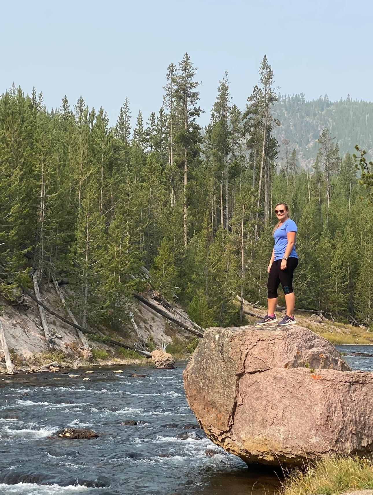 Advisor standing on a rock ledge over a river during the daytime.