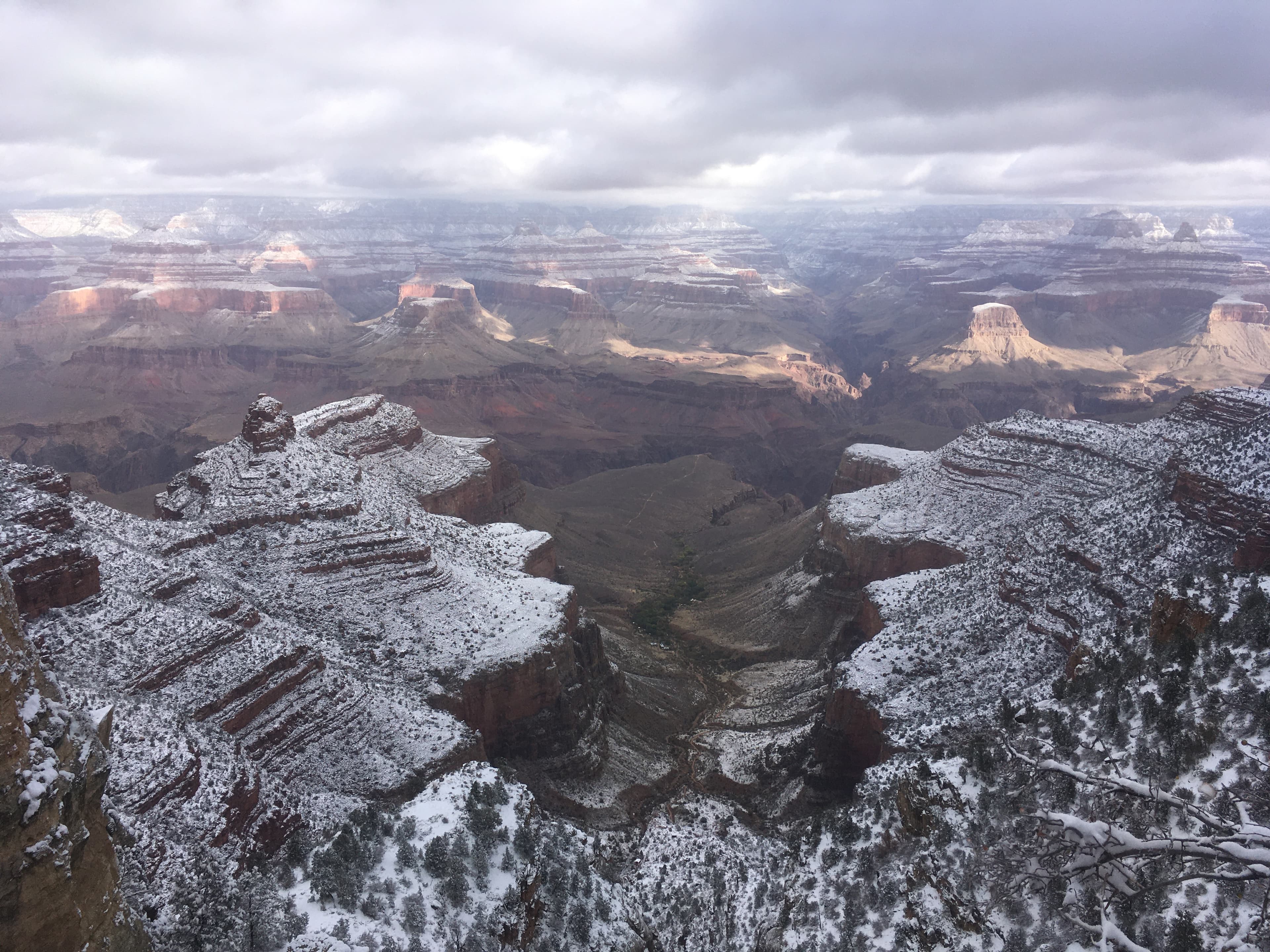 Aerial view of beautiful snowy mountains and a green valley below under cloudy skies