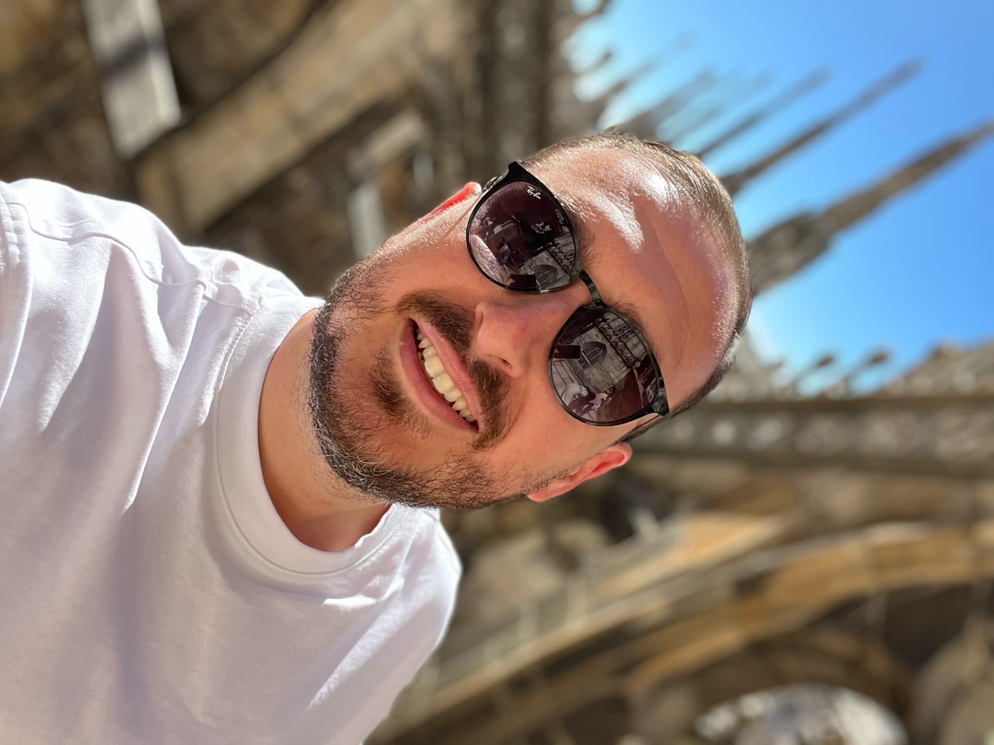 Selfie of advisor with sunglasses and white shirt posing outdoors.