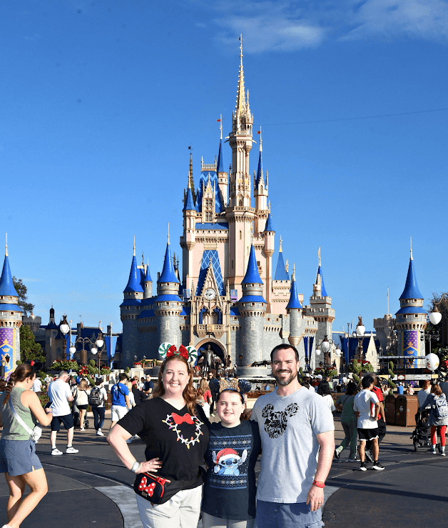 Laura and her family posing in front of Cinderella’s castle at Disney World on a sunny day