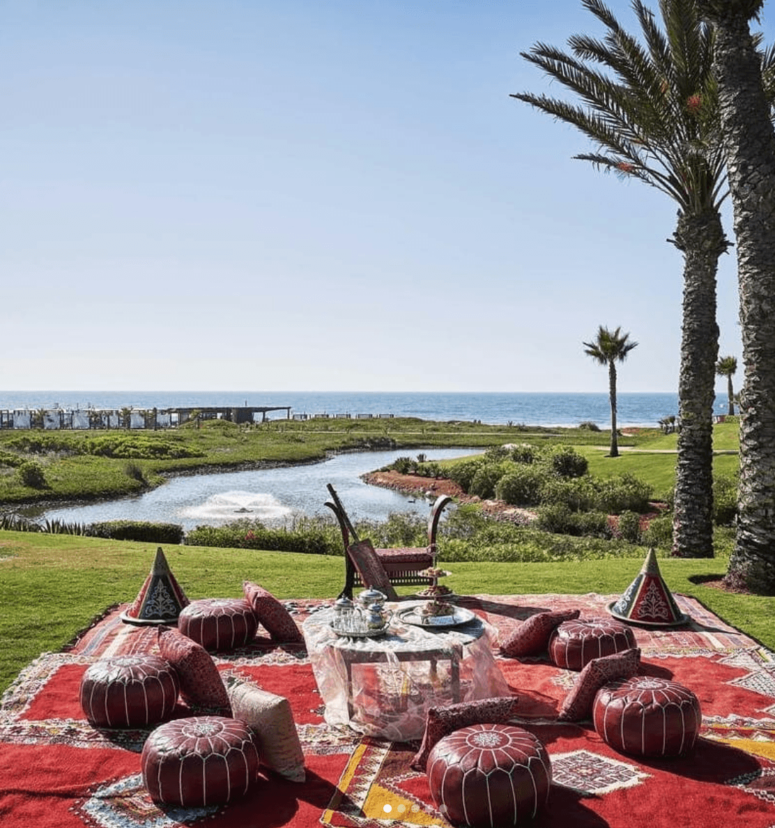 Beautiful view of a red carpet and small stools set around a table overlooking a river and lush landscape leading to sea