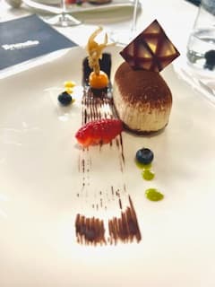 A white plate of dessert with elaborate presentation.