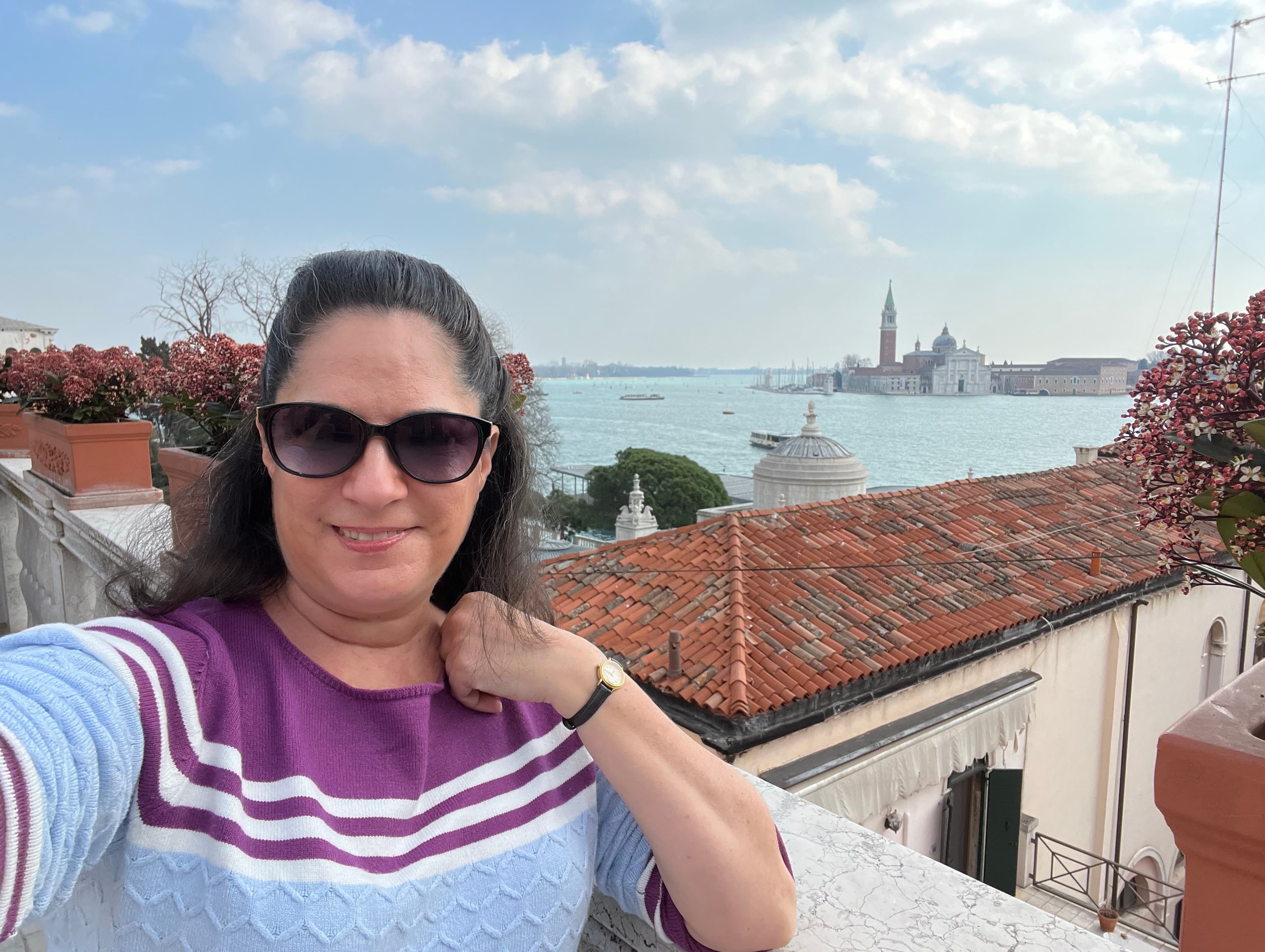 Travel advisor Kristin standing by a wall over looking red-tiled roofs and the ocean.