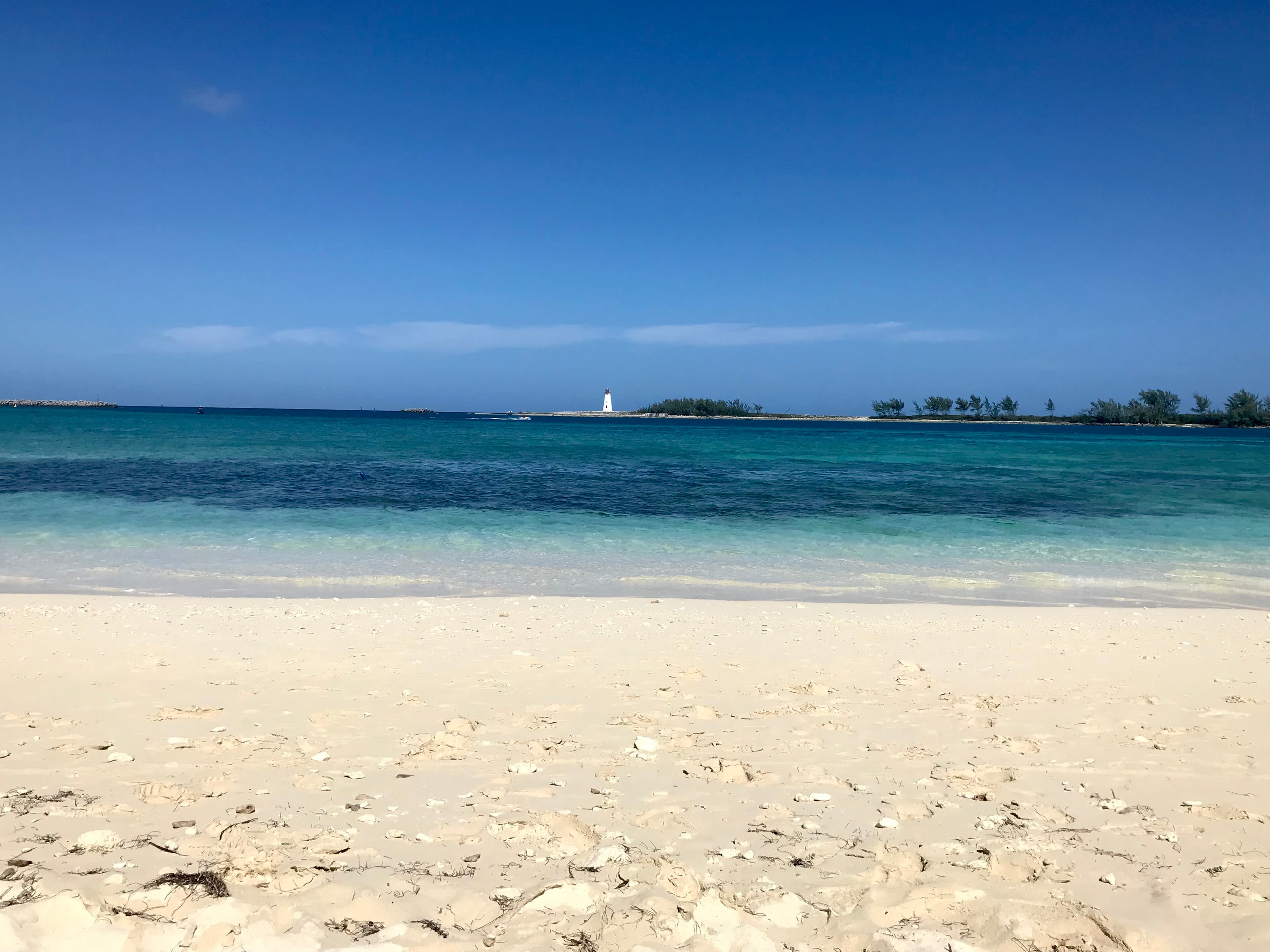 View of a clean white sand beach and calm ocean on a sunny day