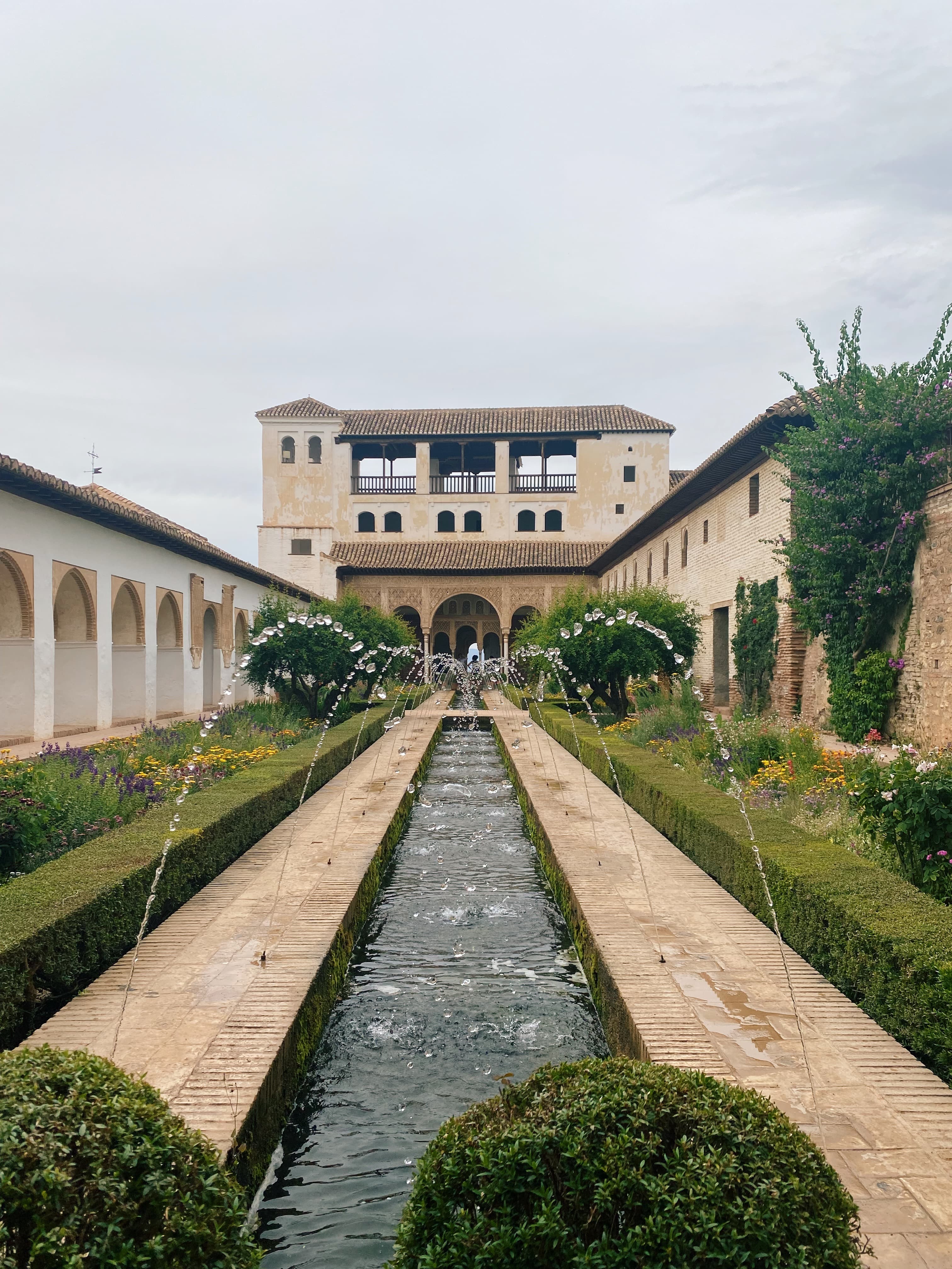 Reflecting pools and fountains run the lake of a courtyard surrounded by greenery overlooking estate porticos and rear doors.