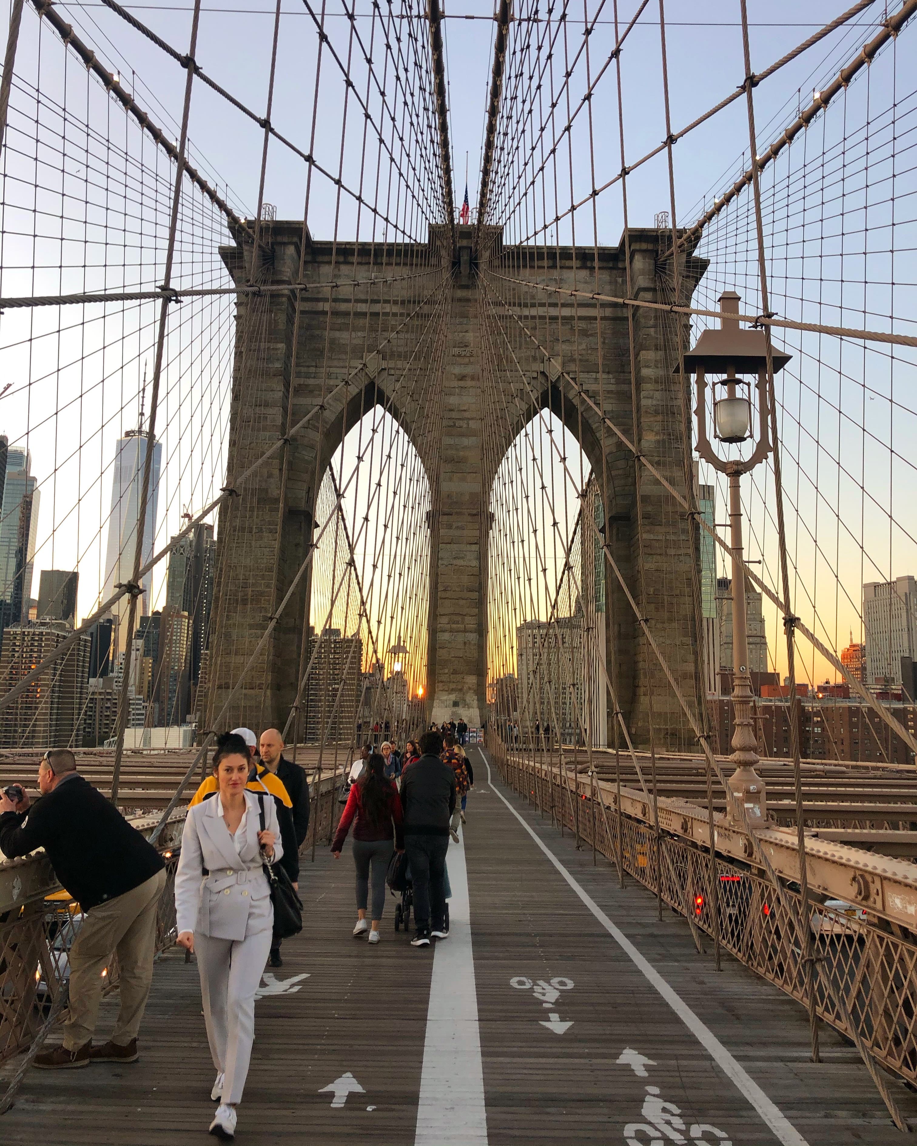 View of the Brooklyn Bridge at sunset with pedestrians walking