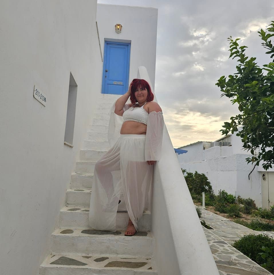 Advisor poses on picturesque white stone steps in front of a sky blue door at dusk.