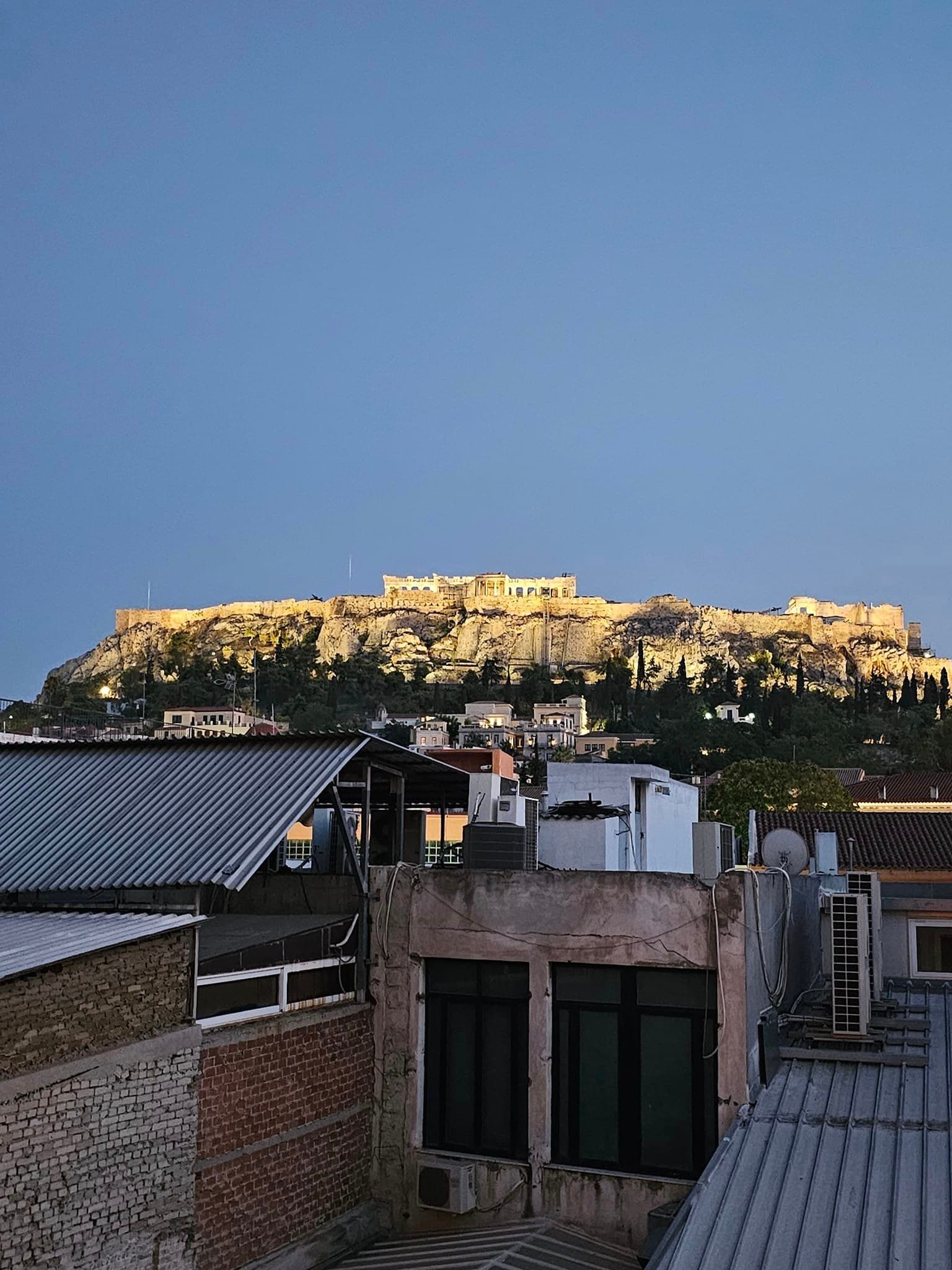 A view of an ancient hilltop lit by sunshine from a city rooftop in the afternoon.