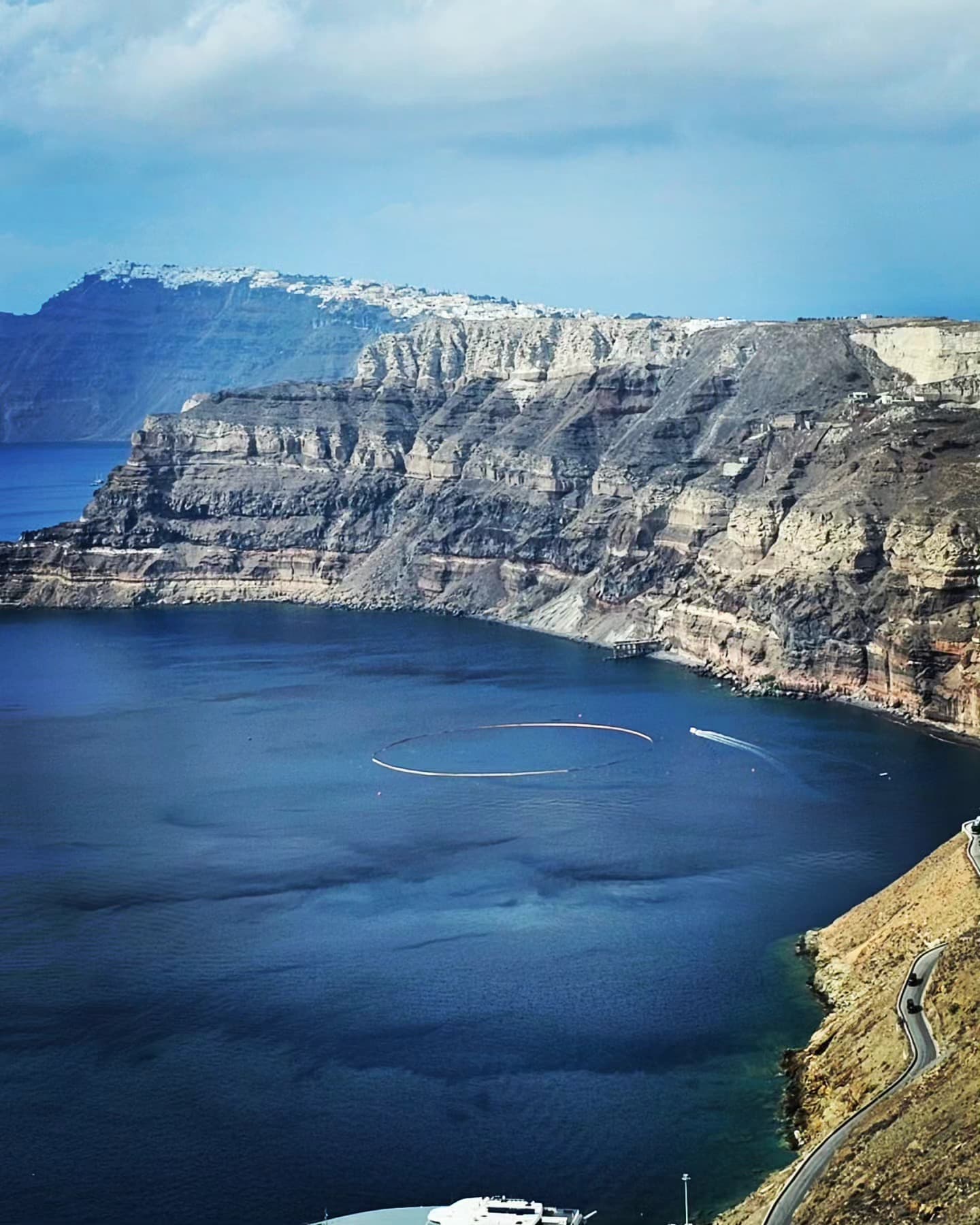 Clear blue waters lap against rocky cliffs in a sunlit day.