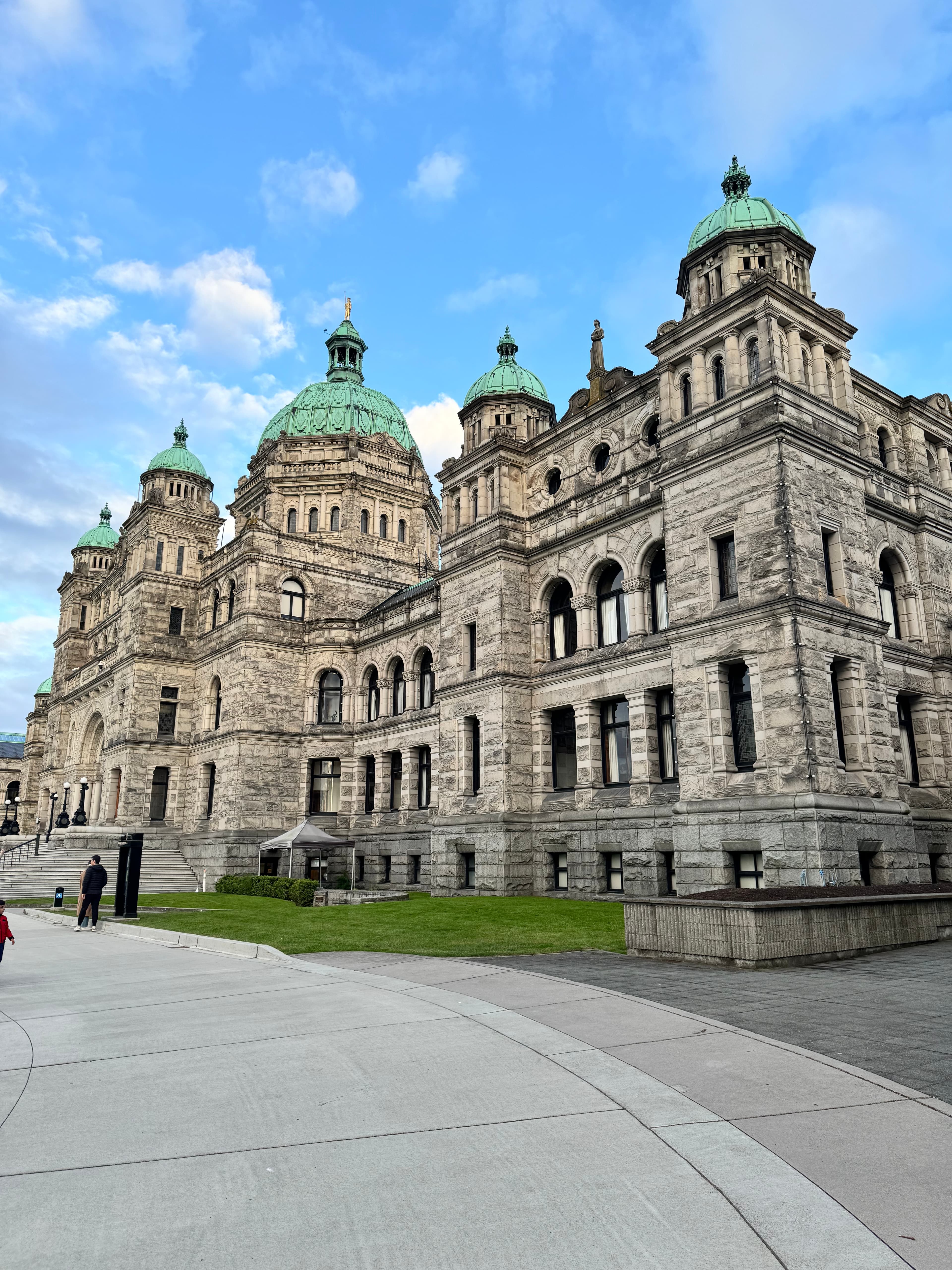 Historic stone buildings stand tall against a clear sky dotted with clouds.