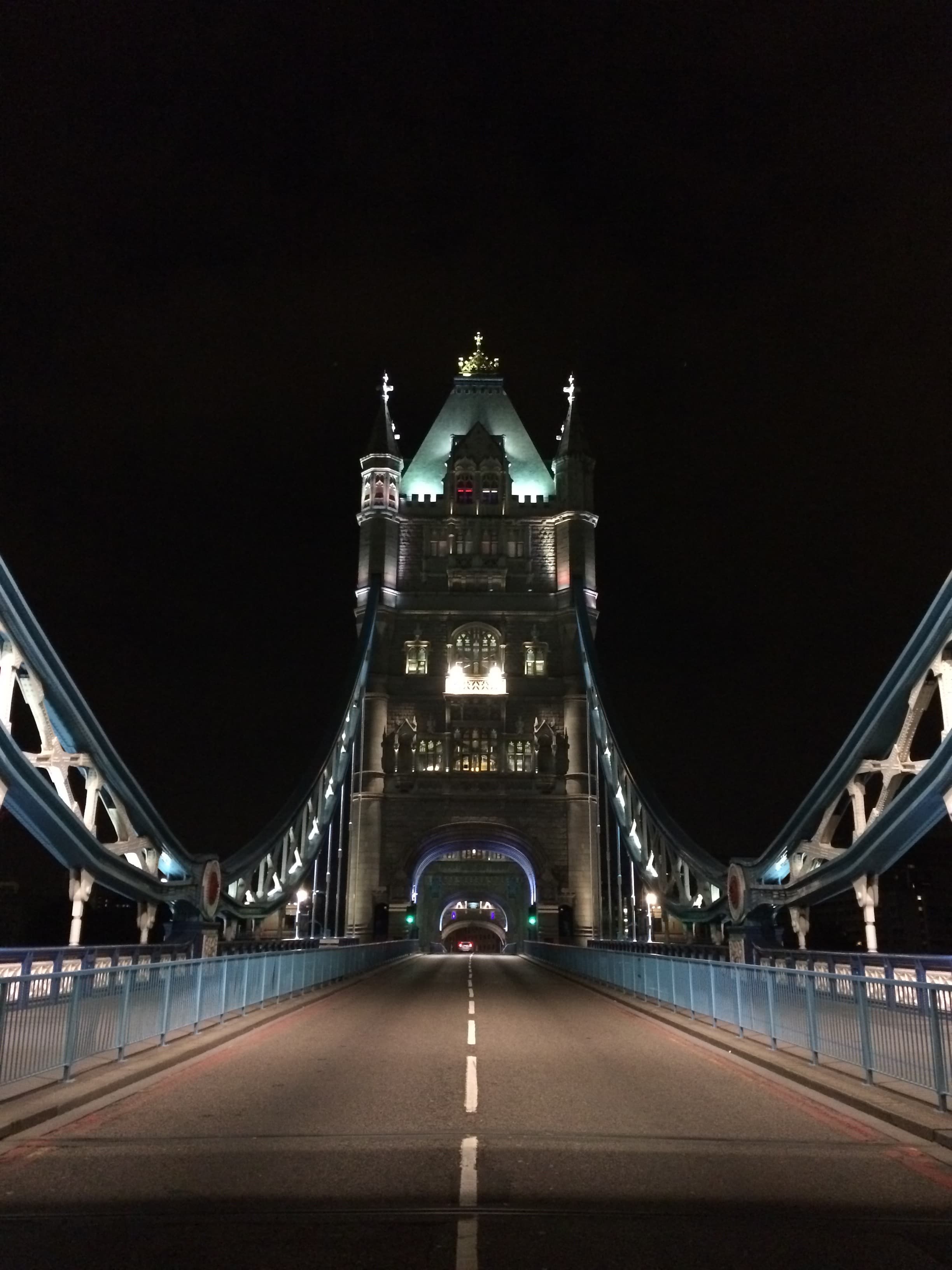 A view of a bridge at night with lights guiding the way.