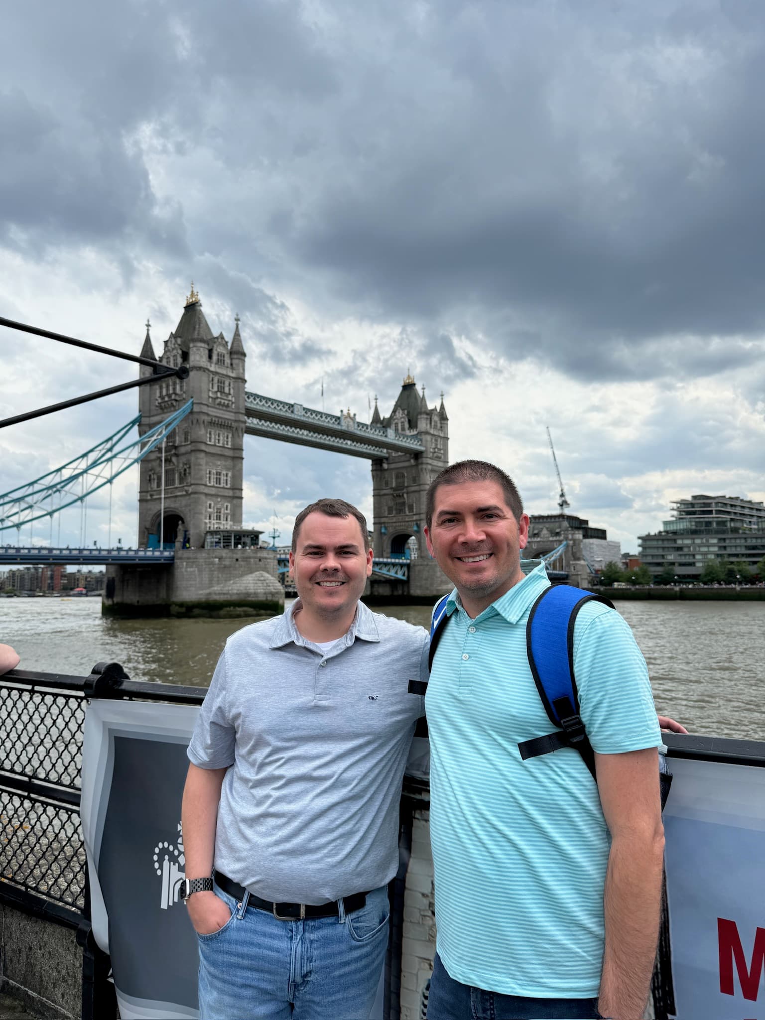 Advisor poses with a bridge stretching into the horizon on a cloudy day.