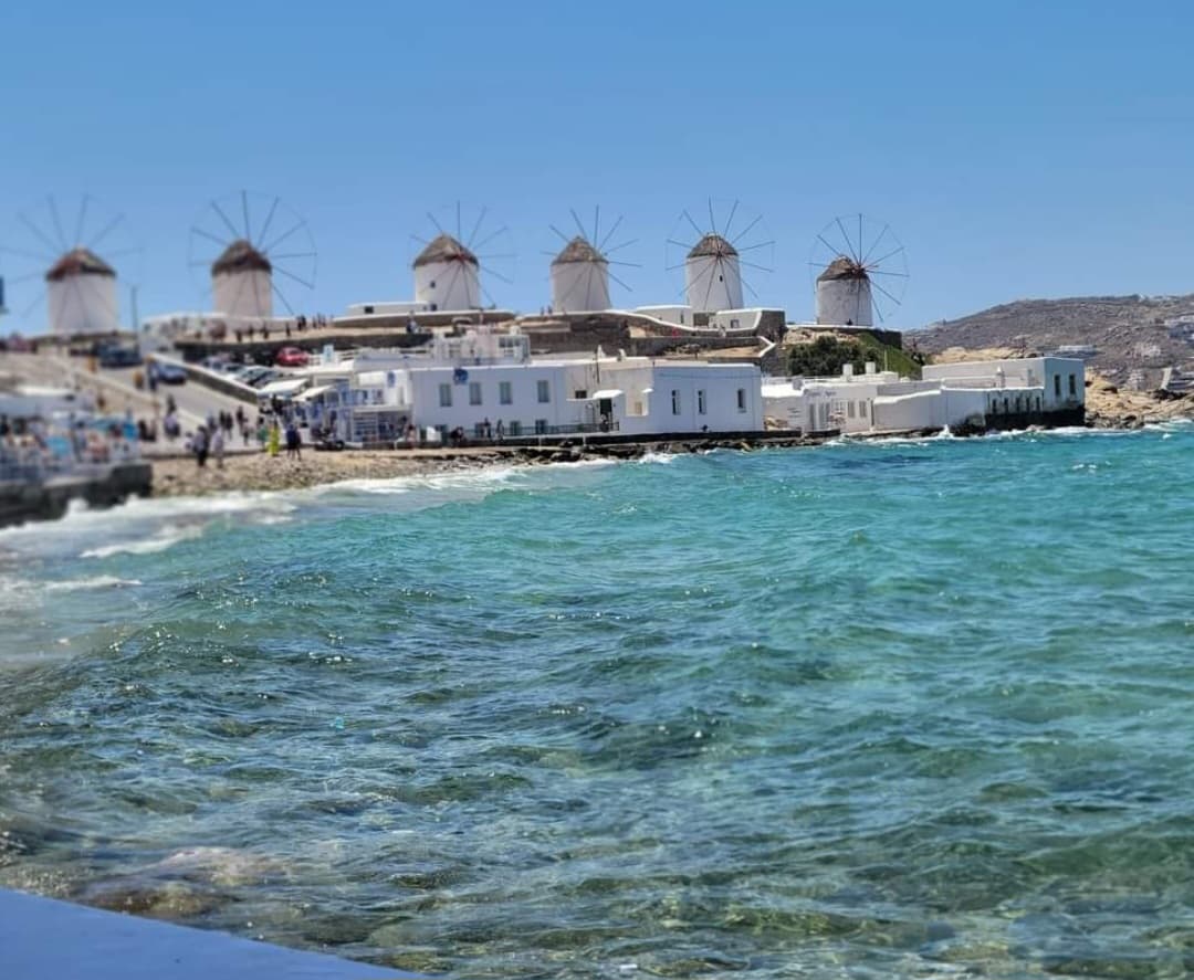 View of a coastal area with white buildings and a rocky beach under clear skies