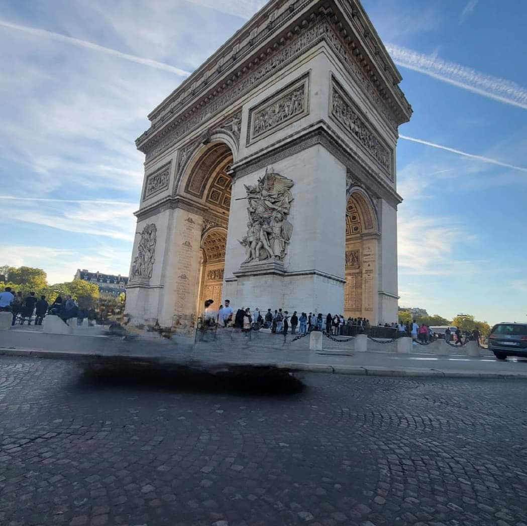 View of the Arc de Triomphe and a line of visitors on a sunny day