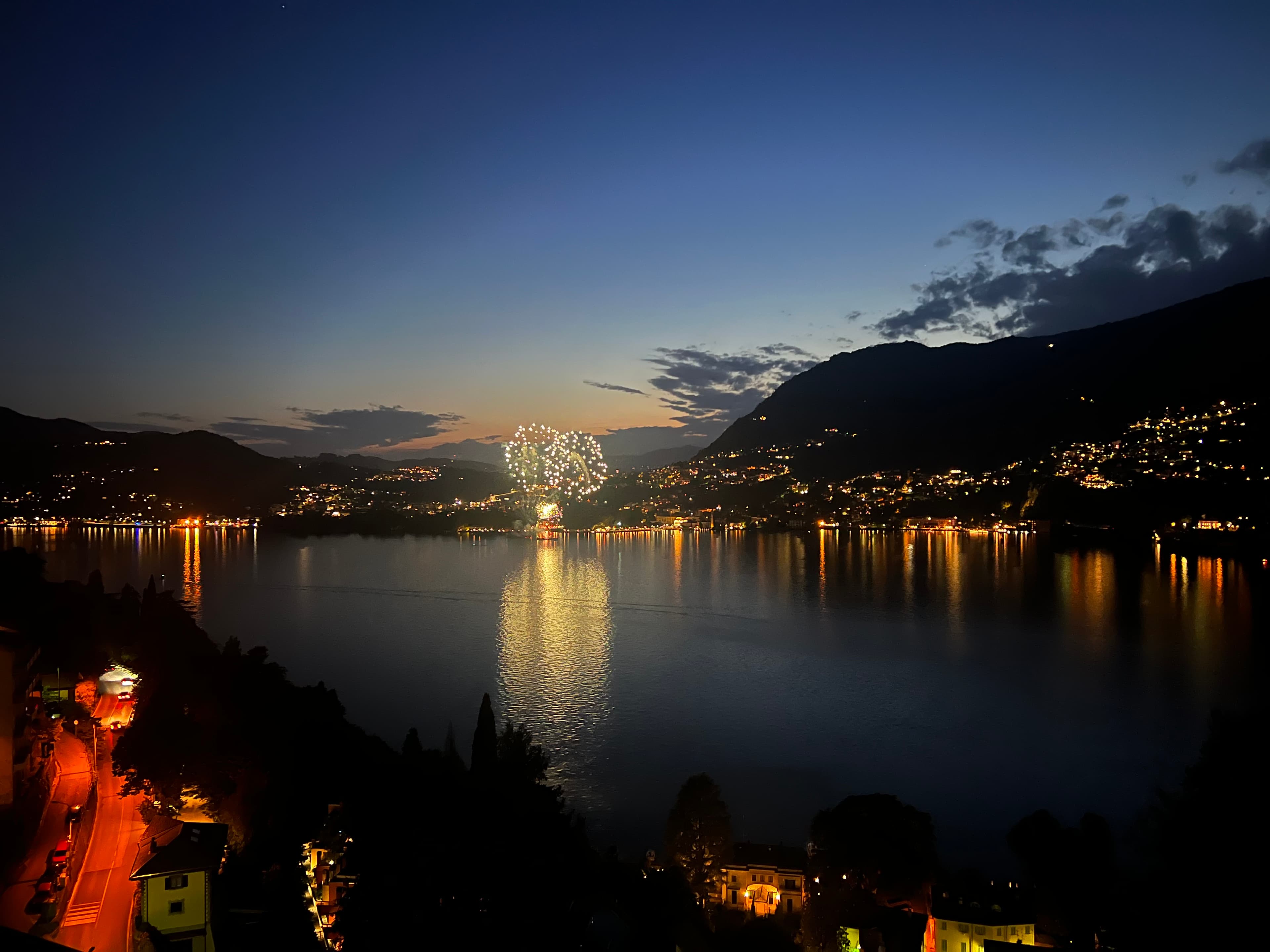 Colorful fireworks lighting up the night sky over Lake Como, creating a stunning reflection on the water below.