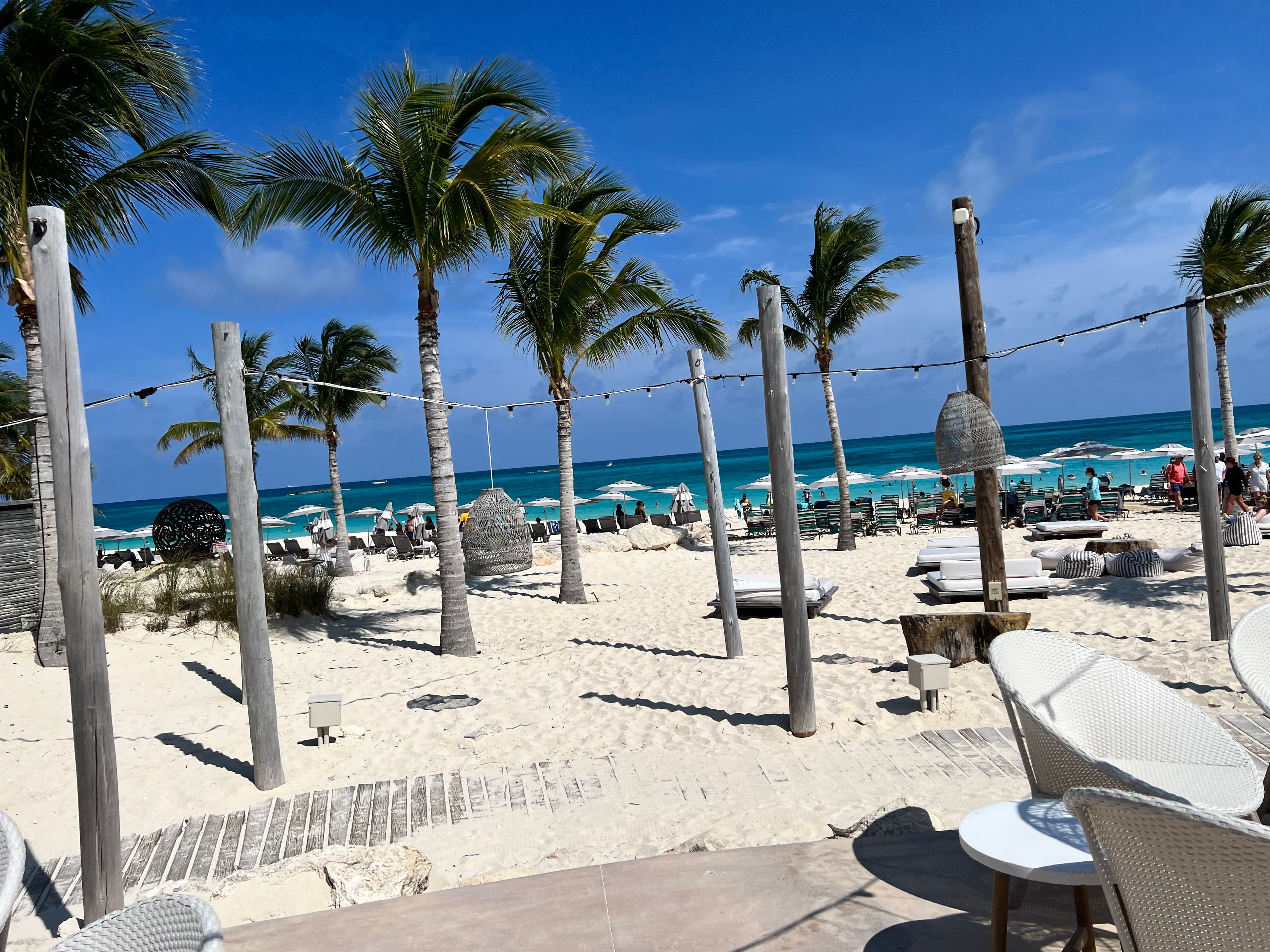 A view of the beach during the day with palm trees in the distance.