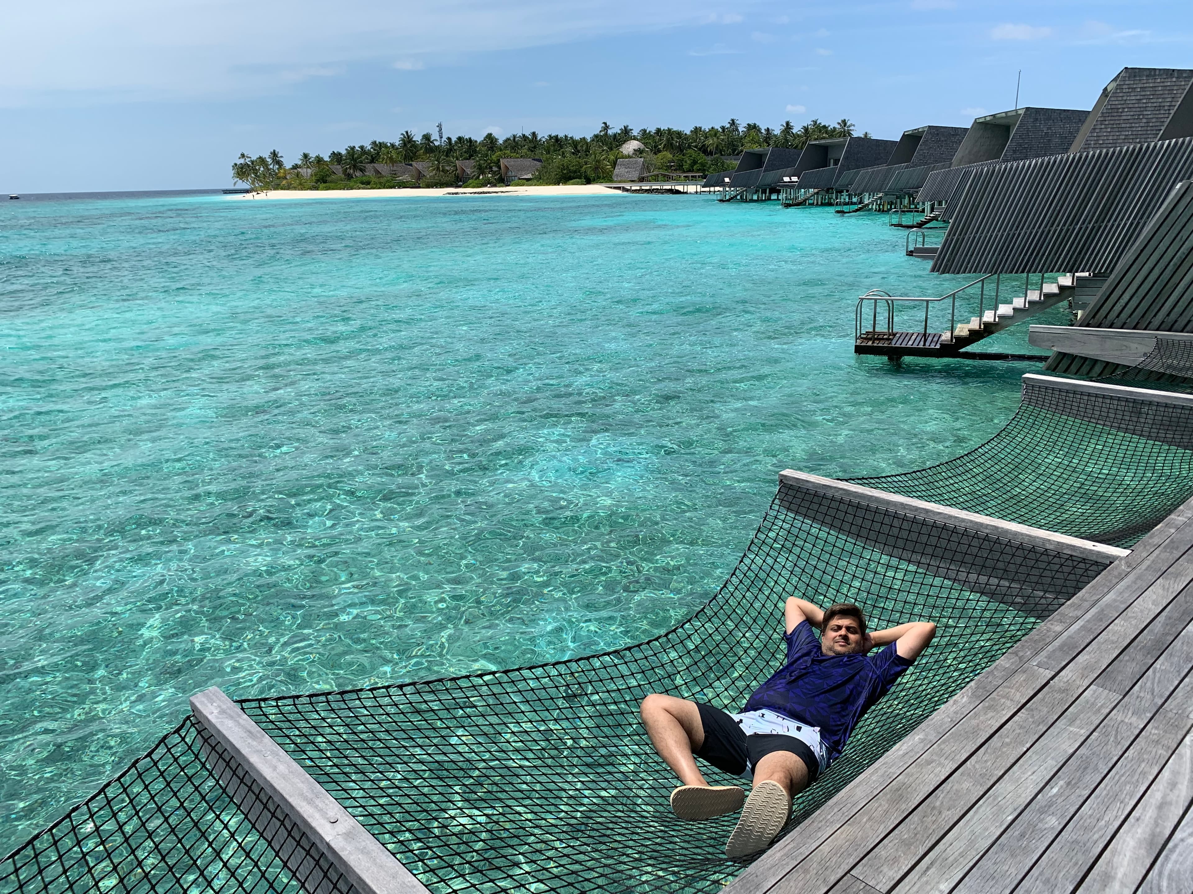 Advisor lounging on a hammock with the ocean below him during the day time.